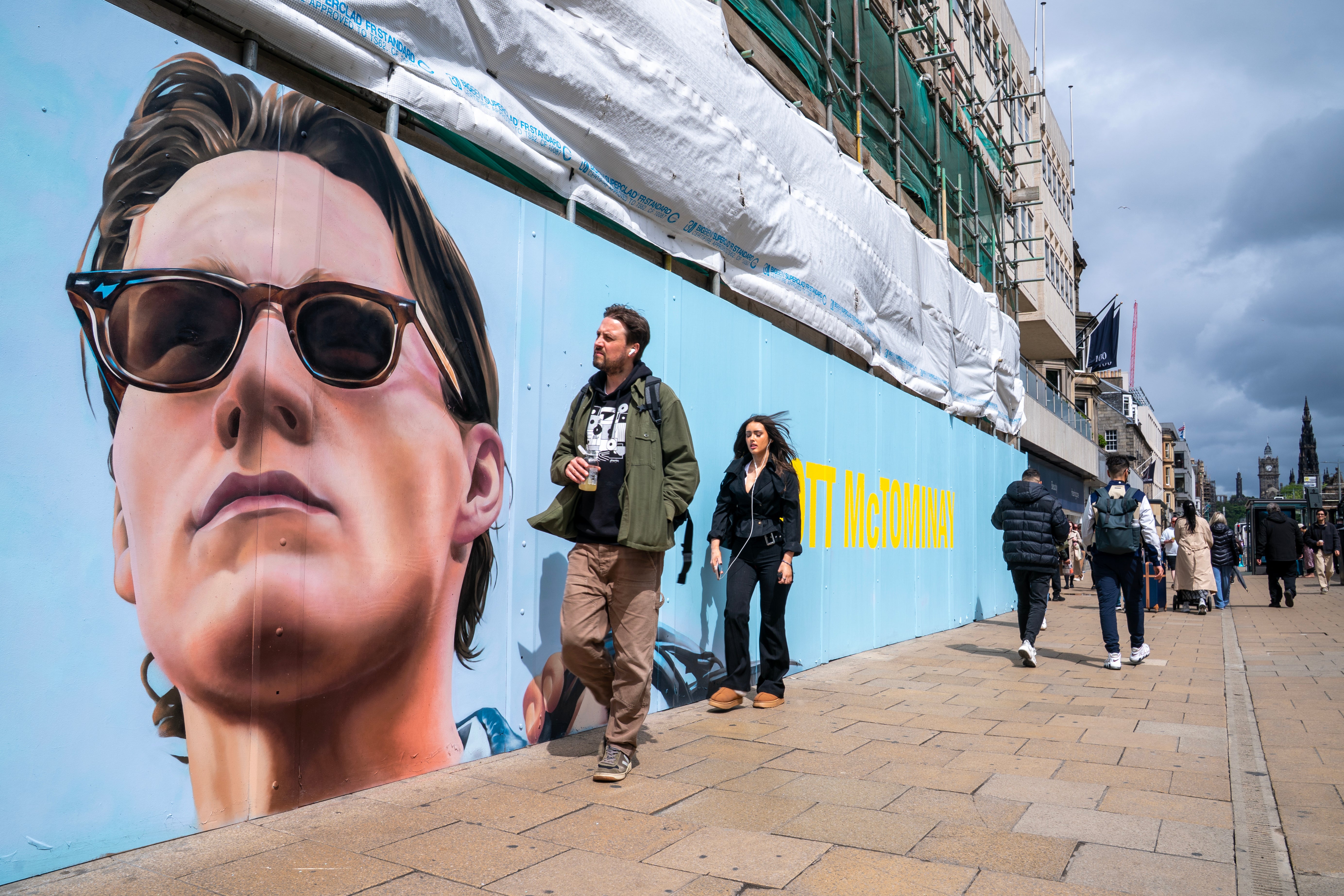 Members of the public pass by a mural featuring Scotland midfielder Scott McTominay on Princes Street in Edinburgh