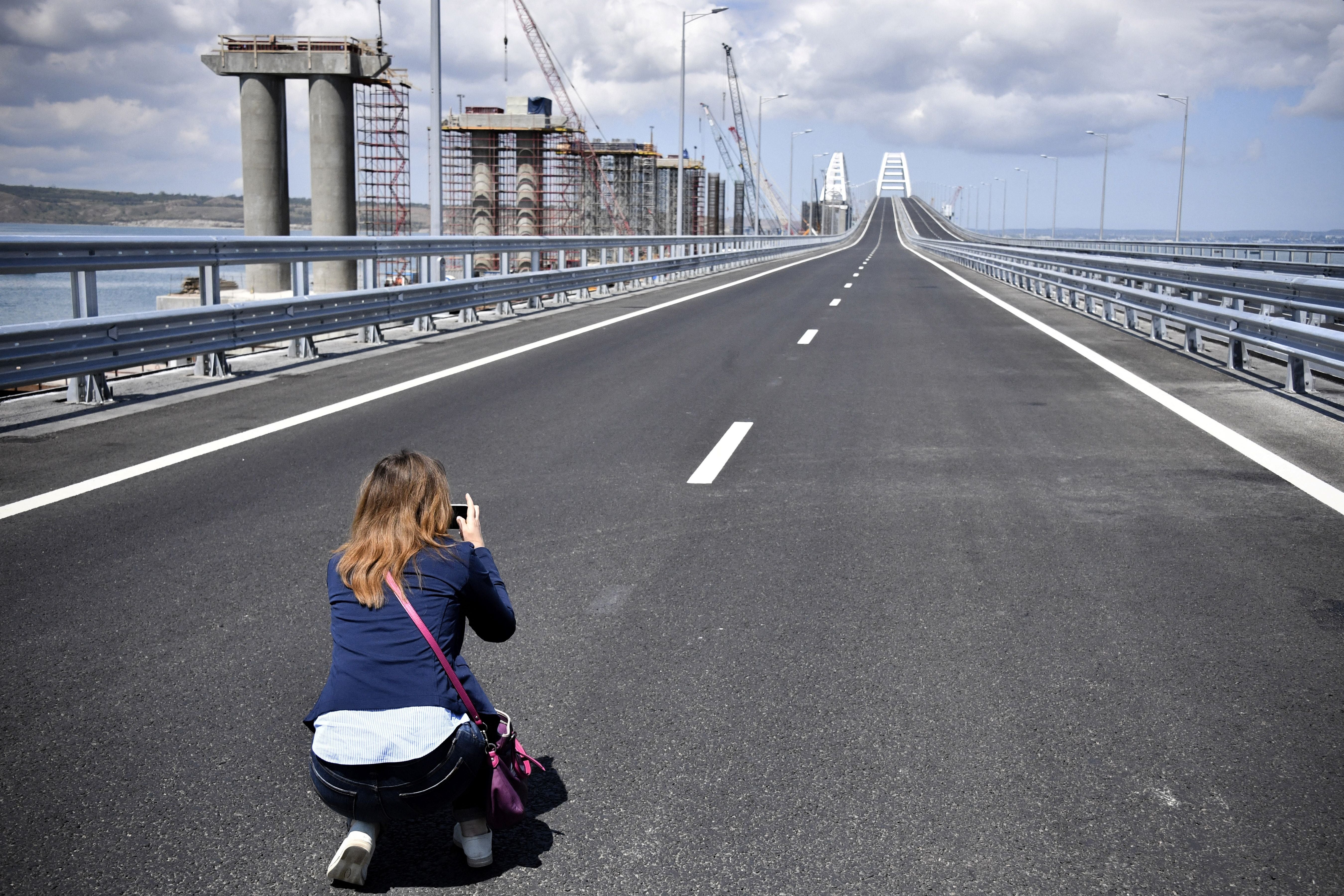 A woman takes a picture prior to the opening ceremony of the 19 km road-and-rail Crimean Bridge passing over the Kerch Straits and linking southern Russia to the Crimean peninsul