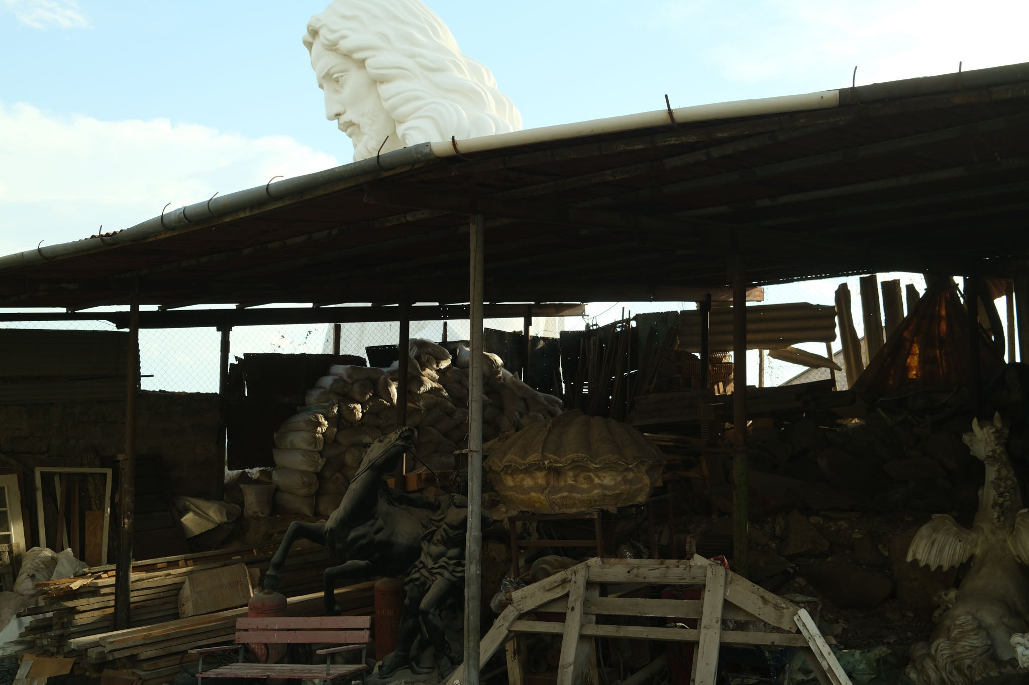 The head of the statue rises above a nearby shed in the yard where the statue is being built