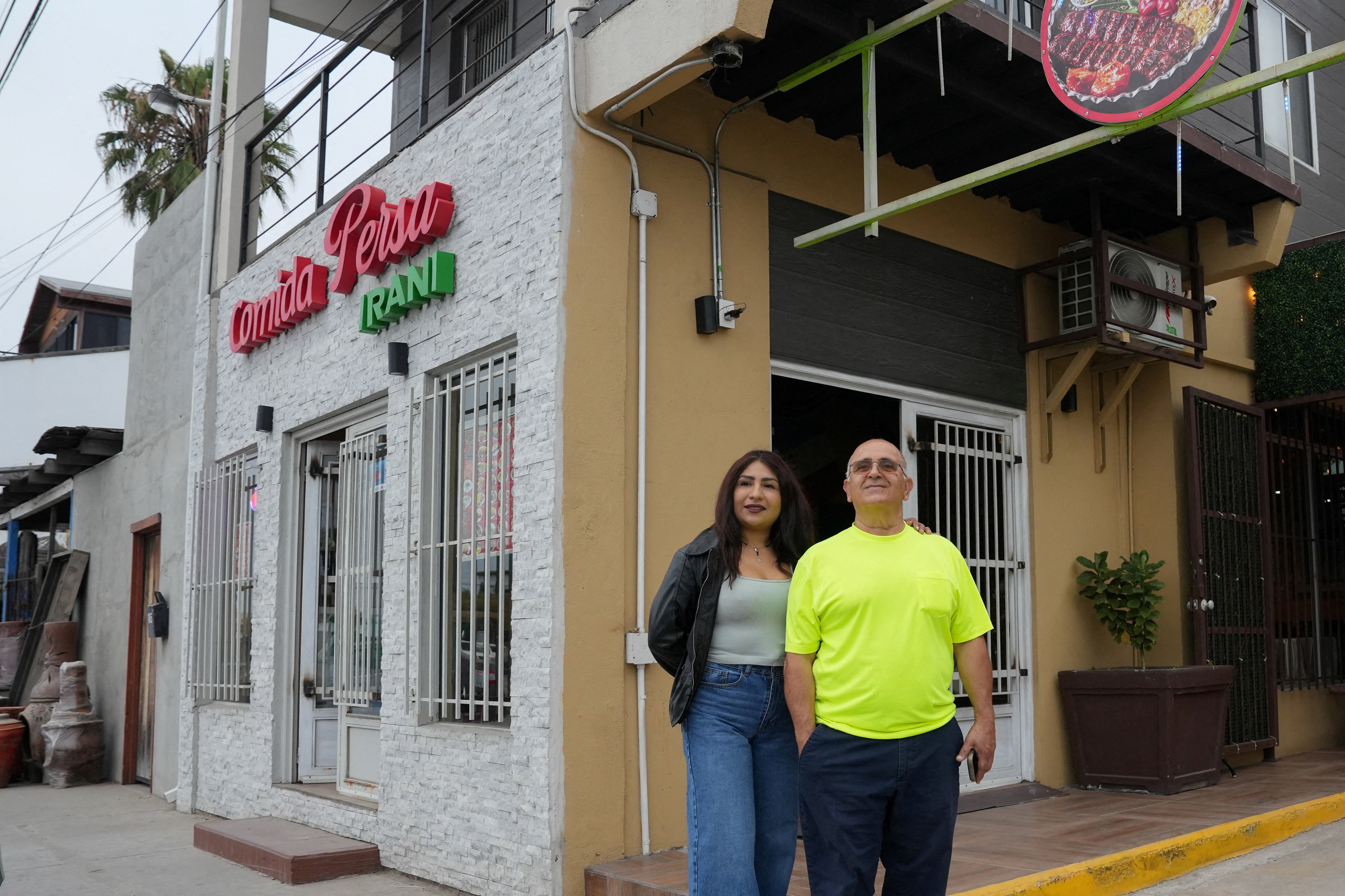 Iranian Saied Assadi, owner of the Comida Persa Iran restaurant, and his Mexican partner Claudia Leonardo pose outside the venue in Rosarito, on the outskirts of Tijuana