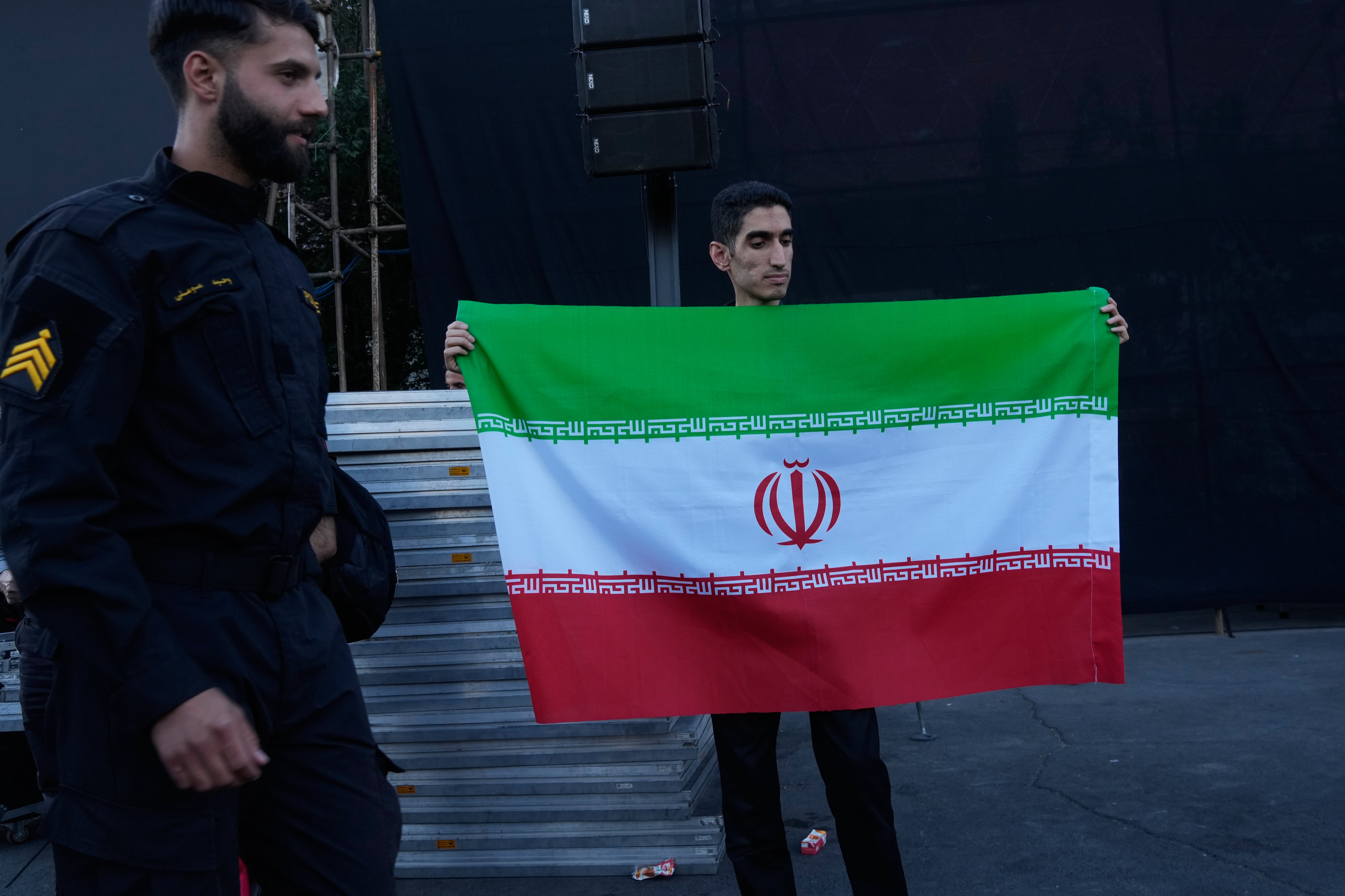 A man holds an Iranian flag while a policeman walks past at the Islamic Revolution square in Tehran, Iran, Sunday, June 14, 2026