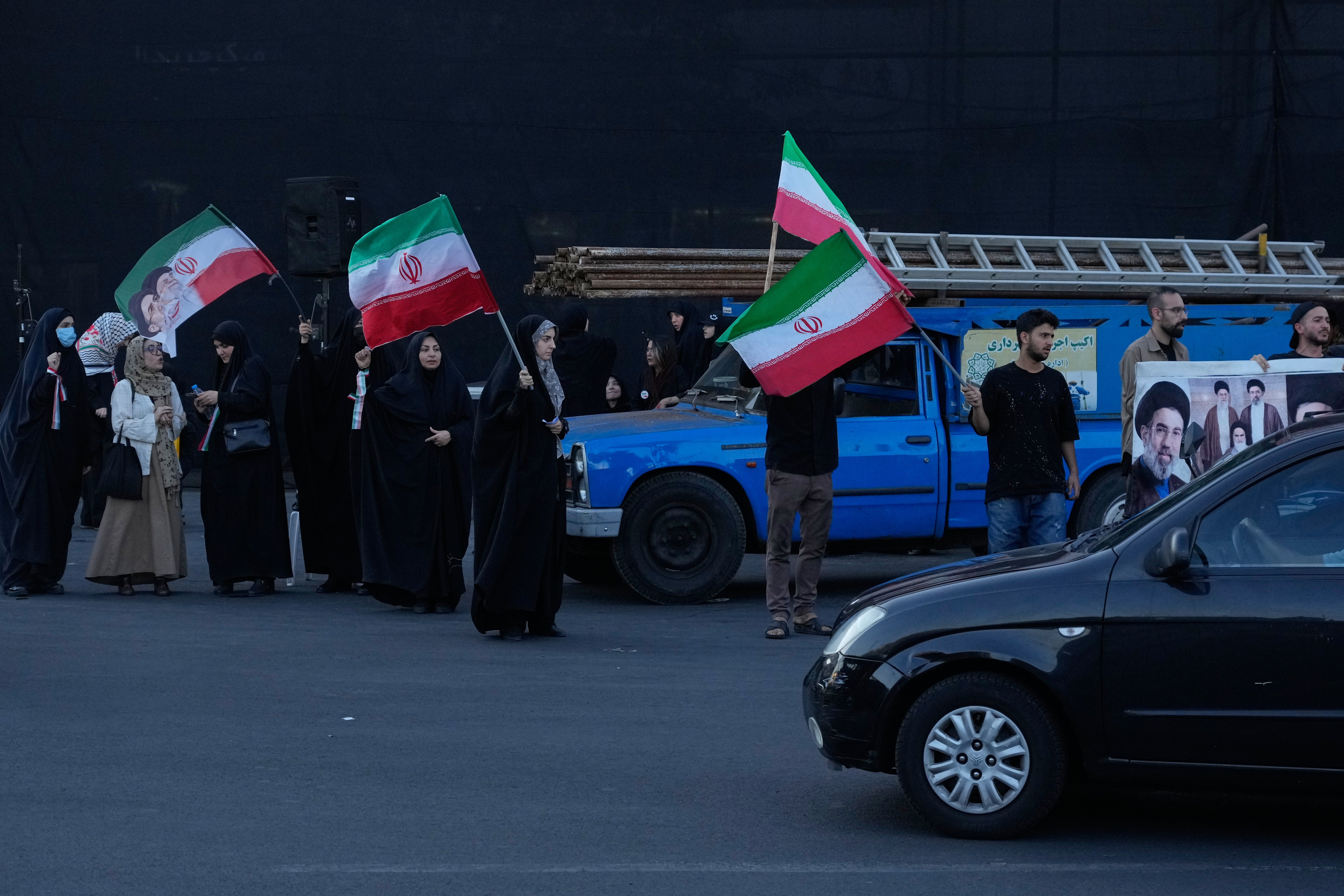 Demonstrators wave Iranian flags in a small group gathering at the Islamic Revolution square in Tehran, Iran, Sunday, June 14, 2026