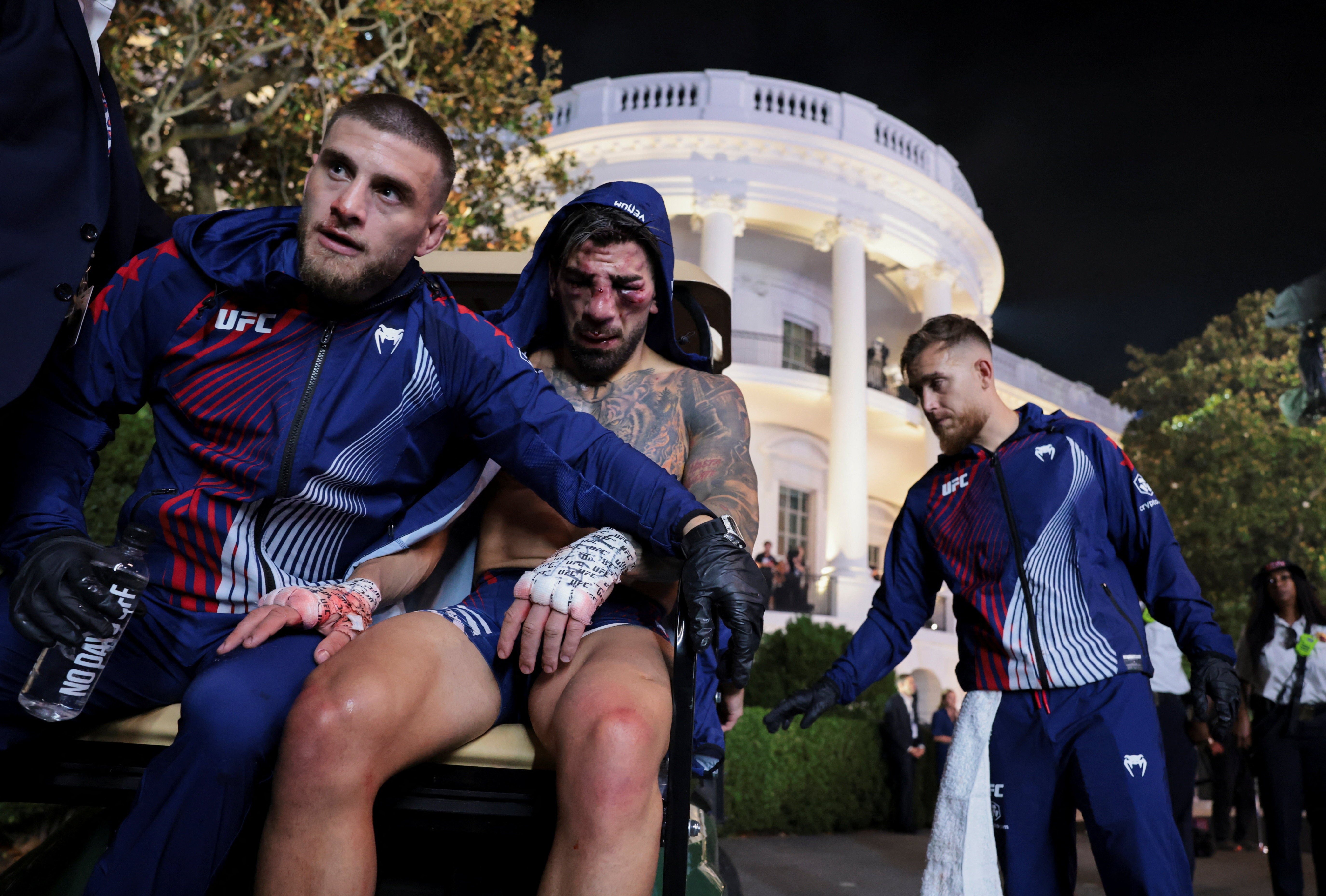 Ilia Topuria (centre) is comforted by his brother Aleksandre (left), who is also his coach