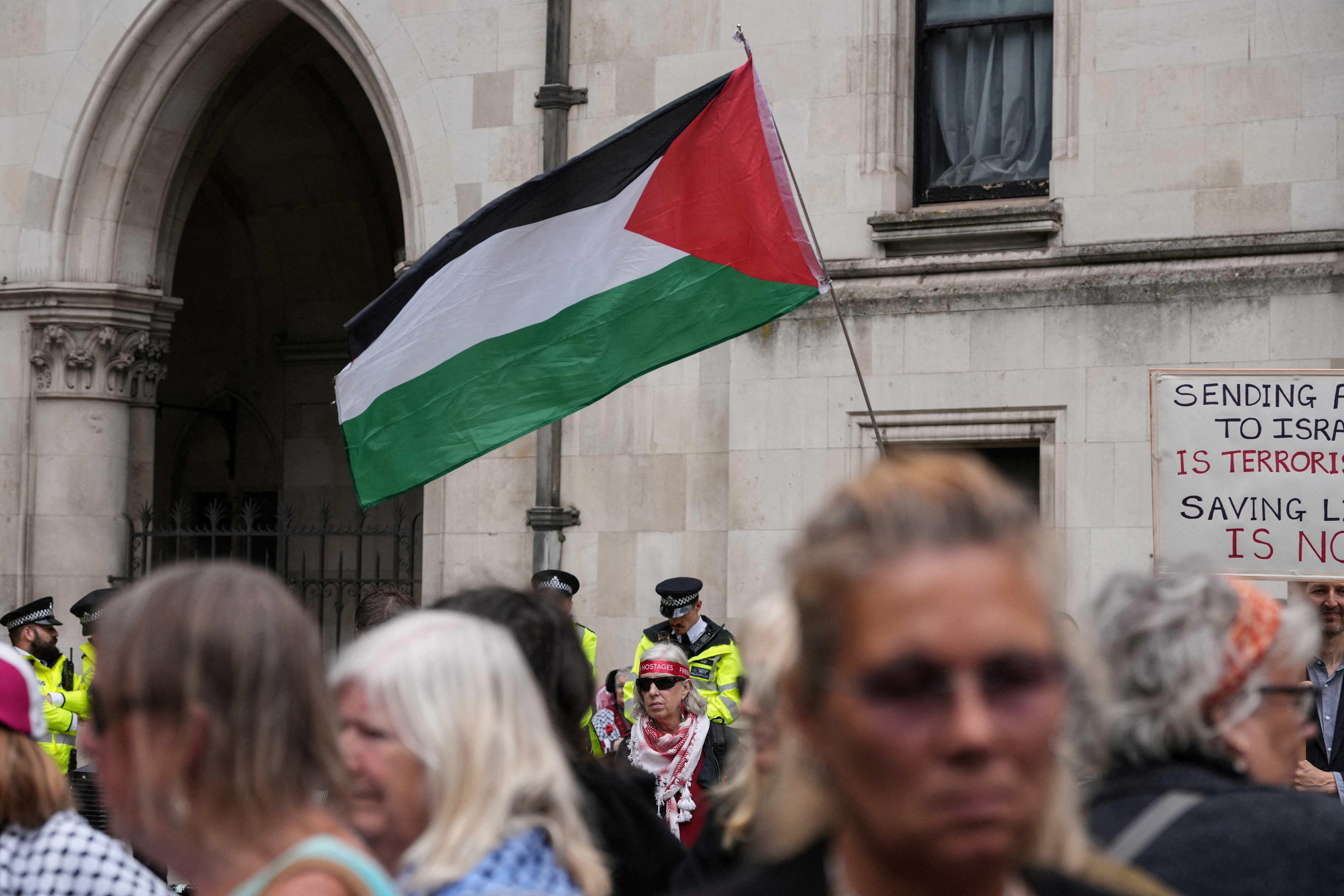 A Palestinian flag is waved as people stand listening to the Court of Appeal ruling on Monday