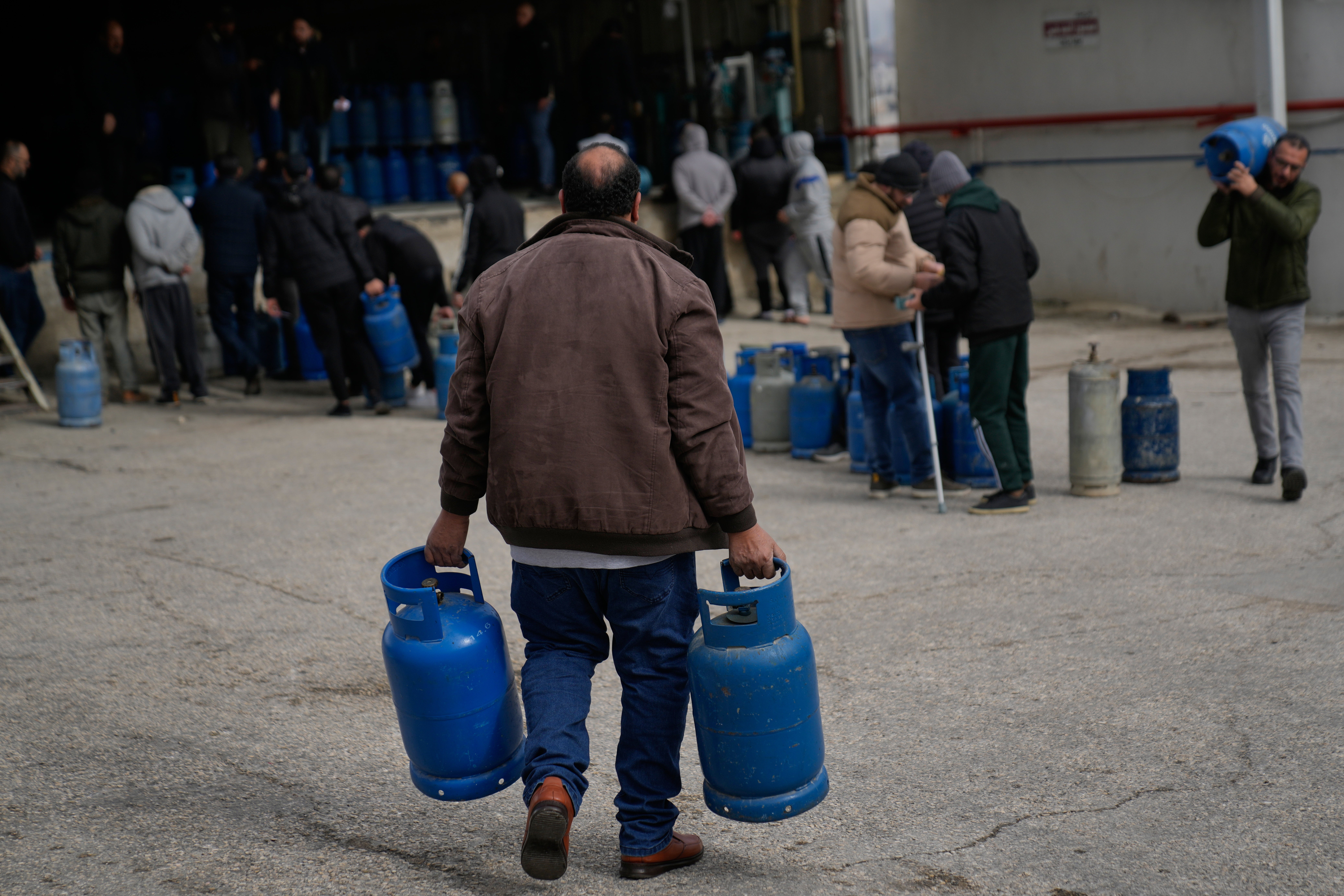 A Palestinian man carries his empty cooking gas cylinders, while he arrives at the main LPG station