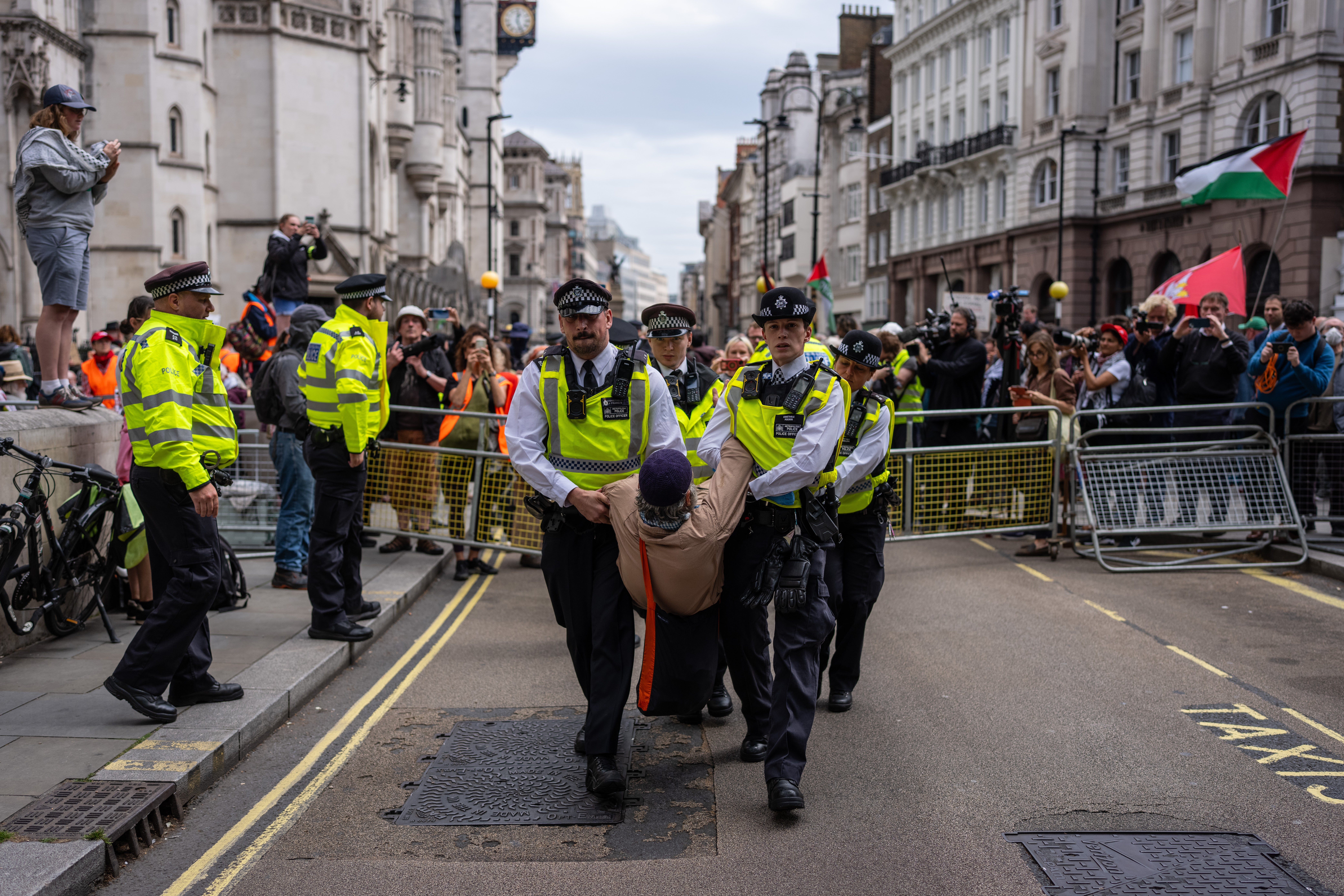 A man is detained by police during a demonstration outside the Royal Courts of Justice on Monday
