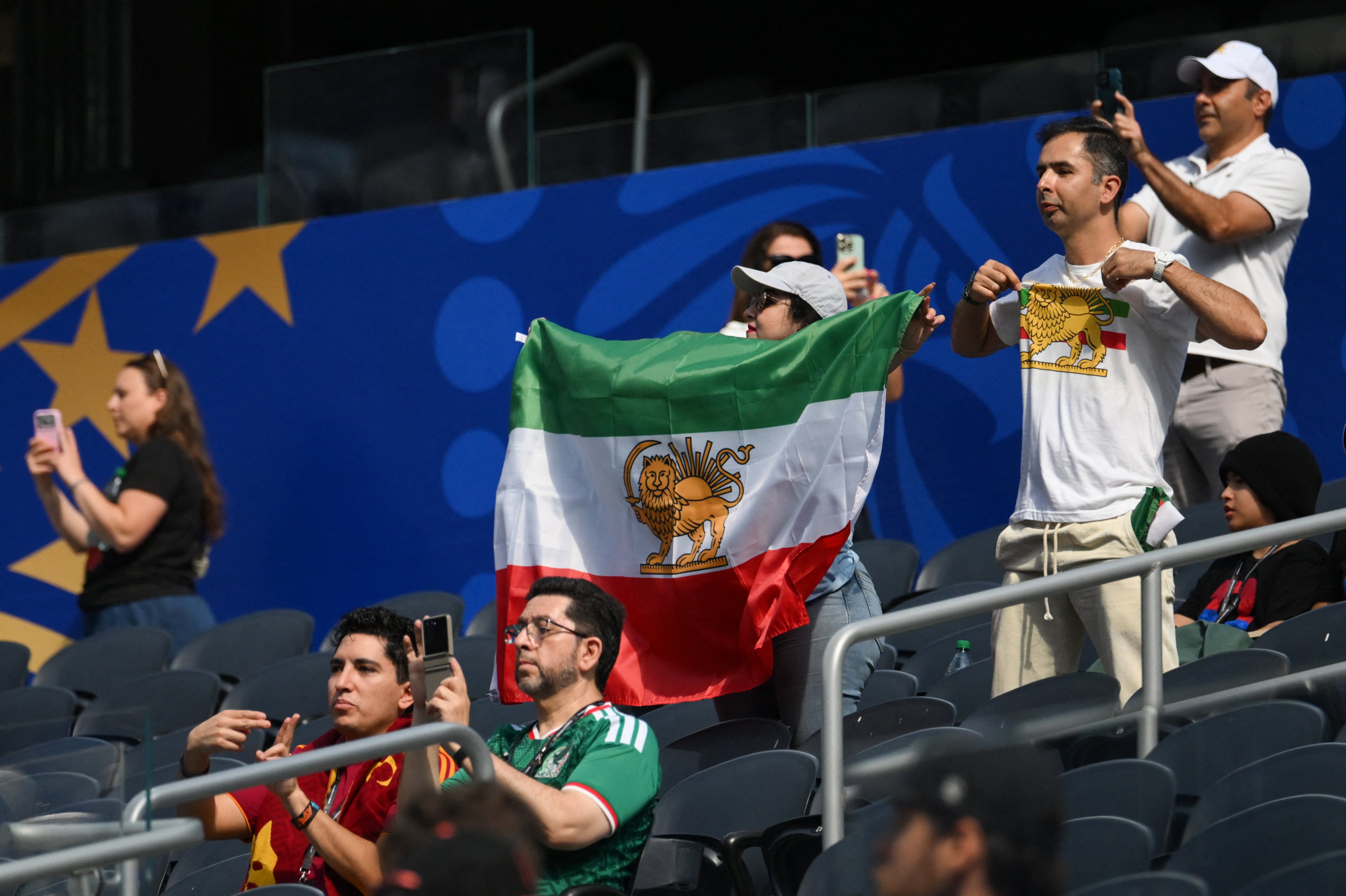 An Iranian fan shows a pre-revolutionary Iranian flag ahead of the 2026 World Cup Group G football match between Iran and New Zealand at Los Angeles Stadium (AFP via Getty Images)