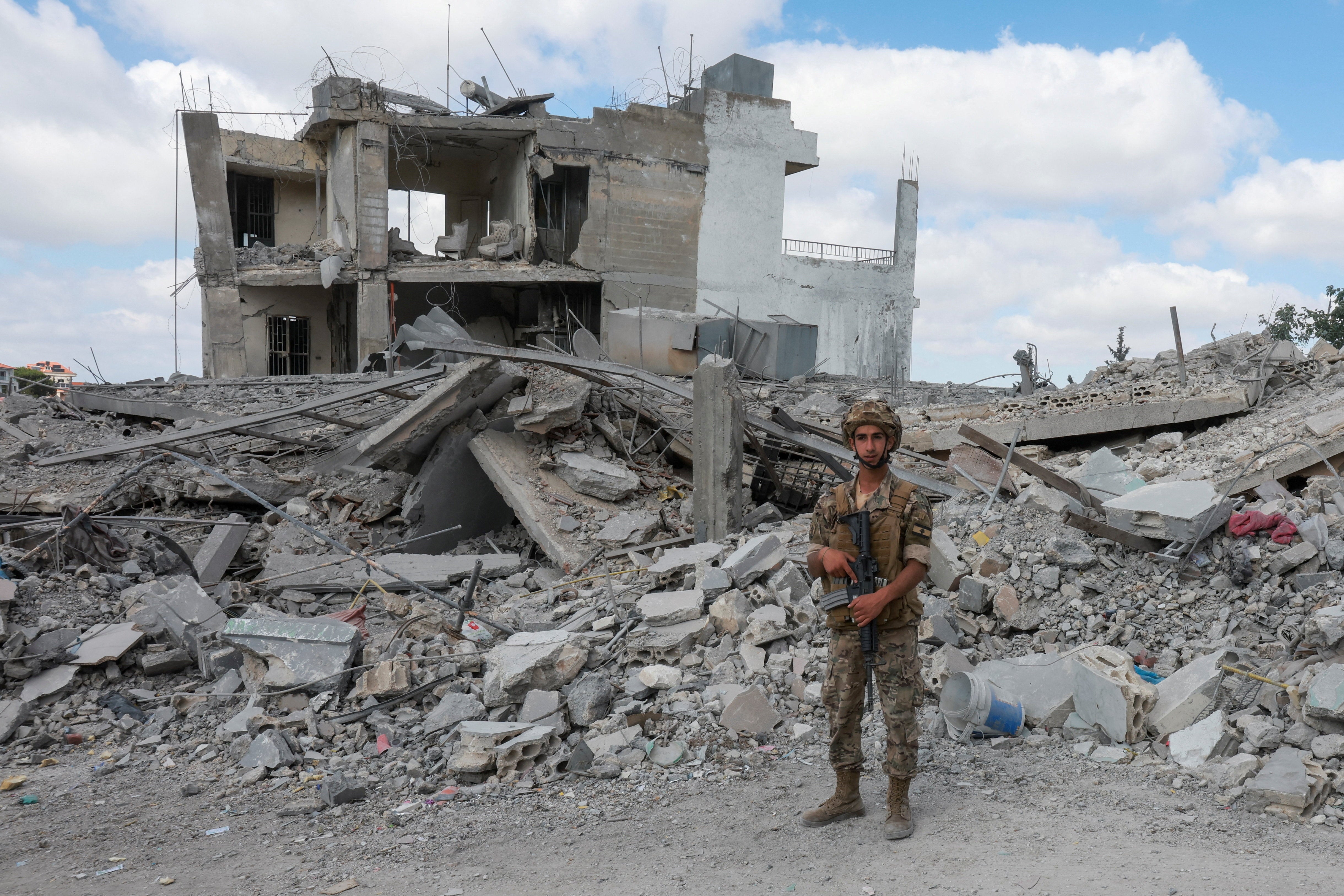 A member of the Lebanese army stands guard near the rubble of destroyed buildings, as people make their way back to their homes, following a peace deal between the United States and Iran, in Bir Al-Salasil, Tyre district,