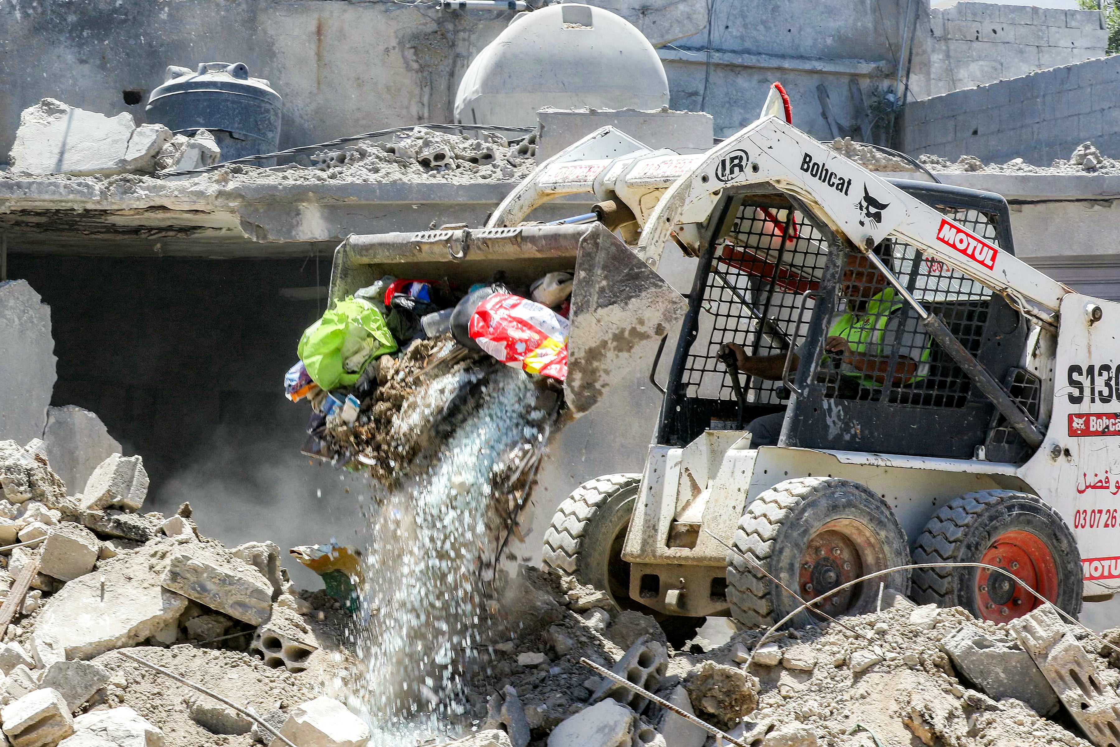 A worker pilots a small excavator to remove the rubble of a destroyed building in the village of Deir Qanoun al-Nahr in southern Lebanon on June 16 (AFP/Getty)