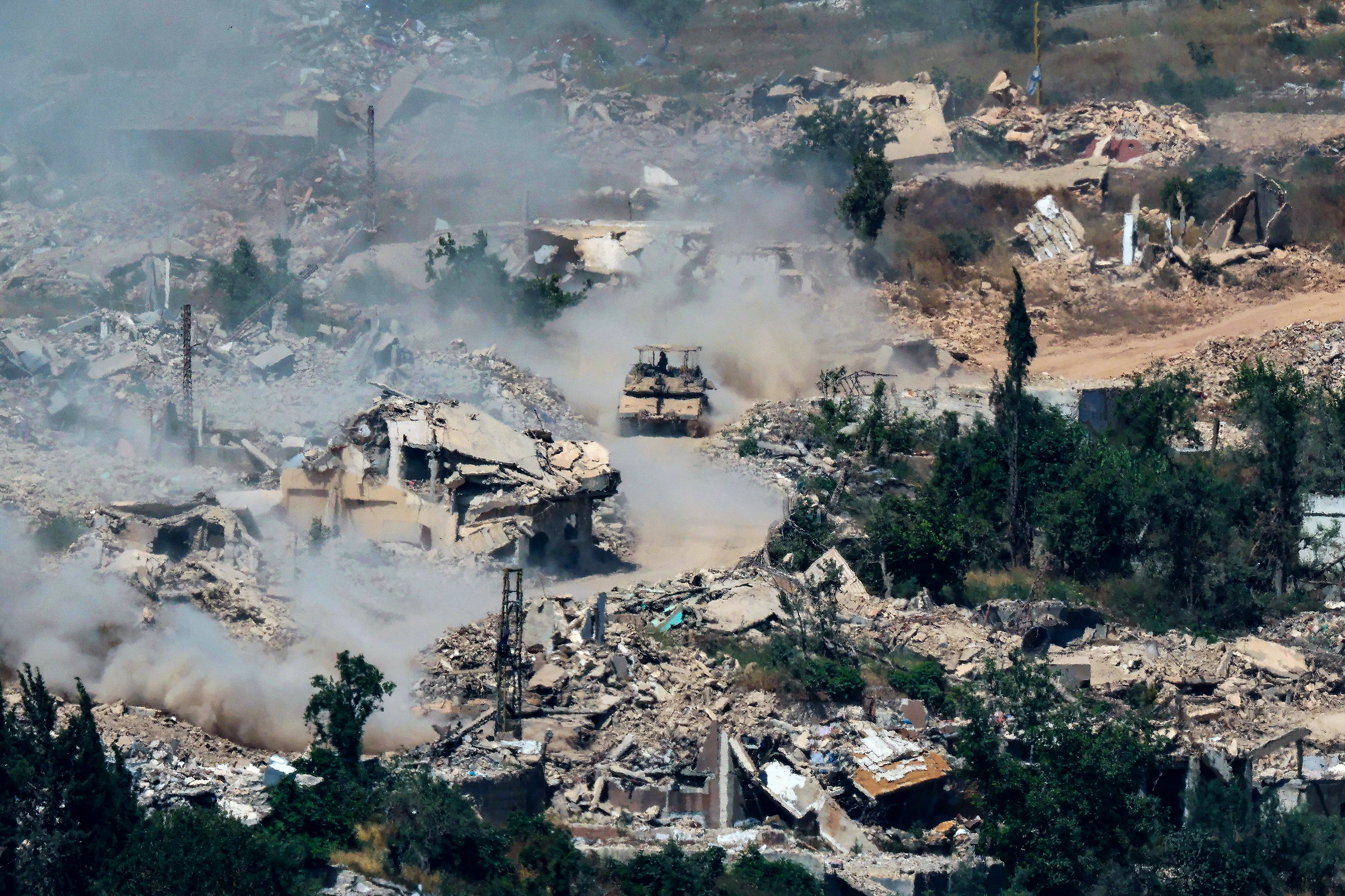 Israeli Merkava tanks driving along a road past destroyed buildings in southern Lebanon on June 17, 2026