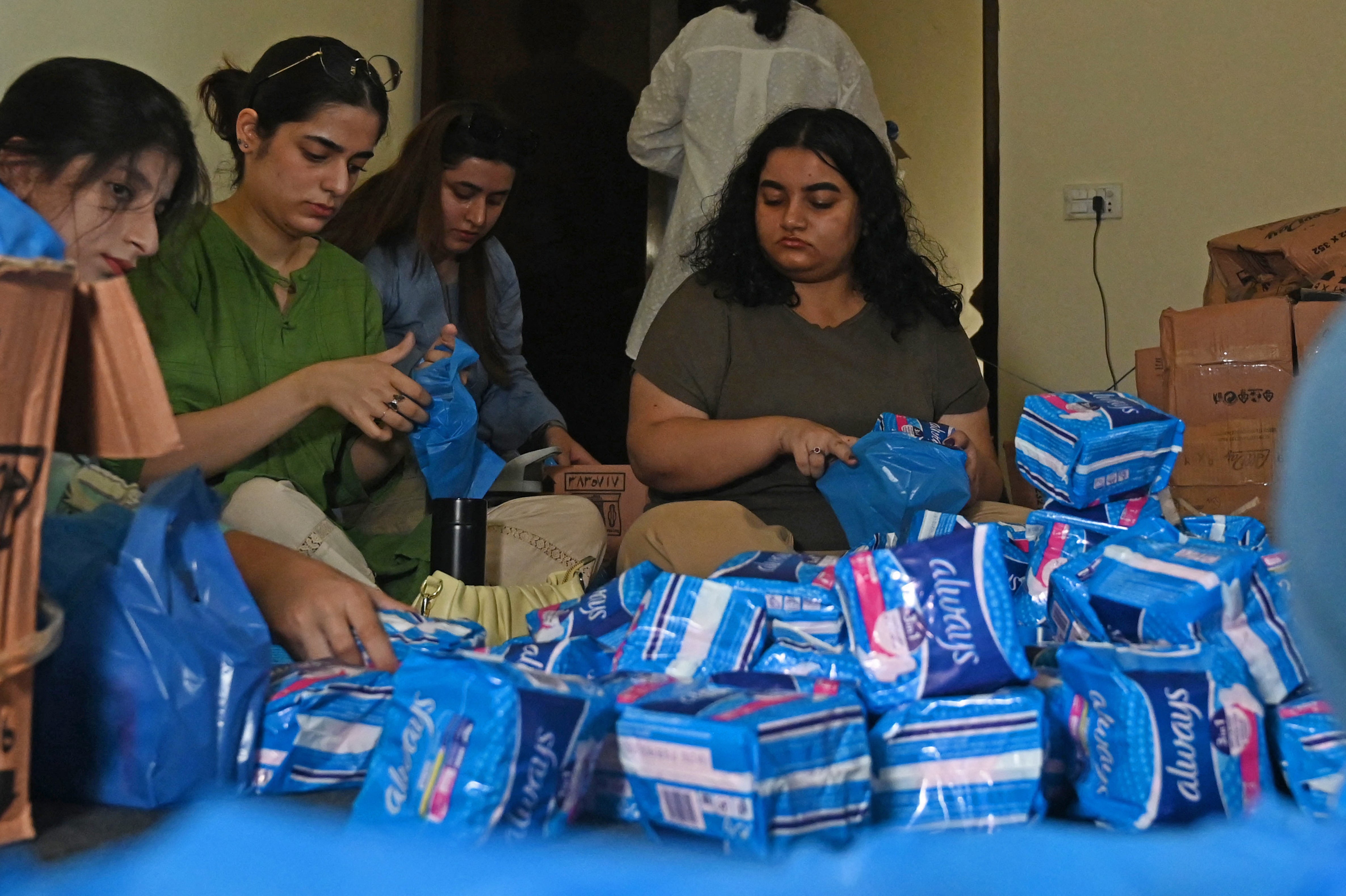 Members of a non-governmental organisation pack sanitary pads for women displaced by massive flooding, in Lahore on August 31, 2022