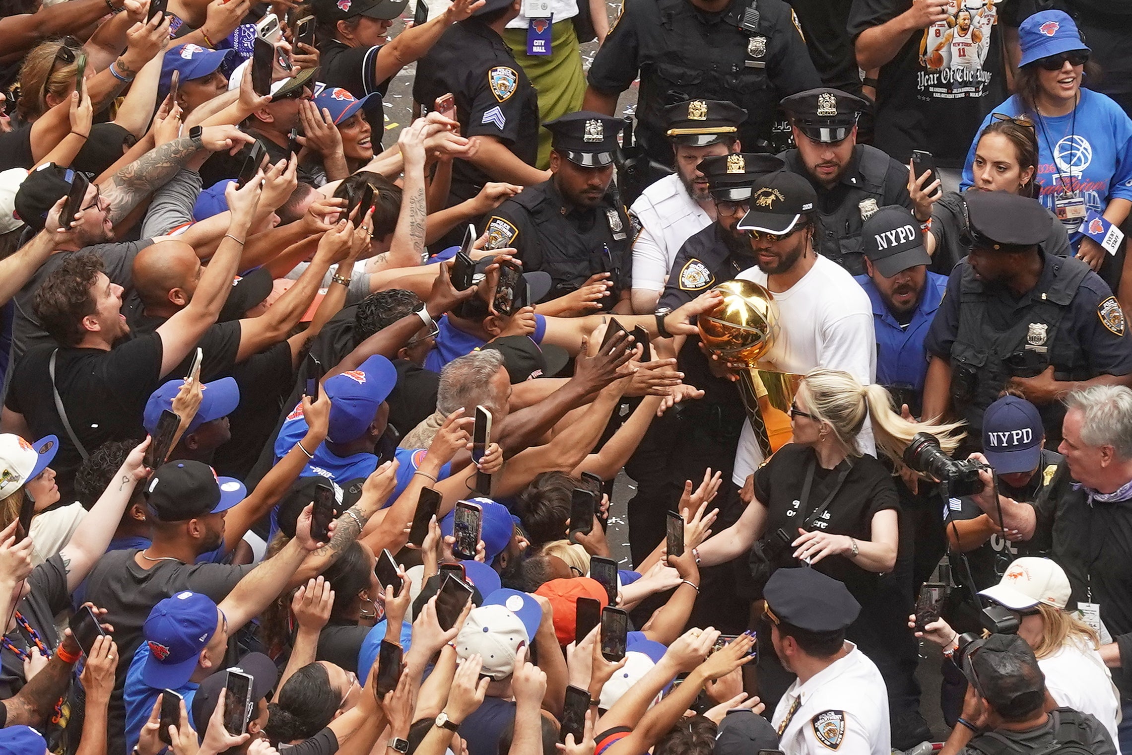 Jalen Brunson carries the trophy alongside fans during the parade