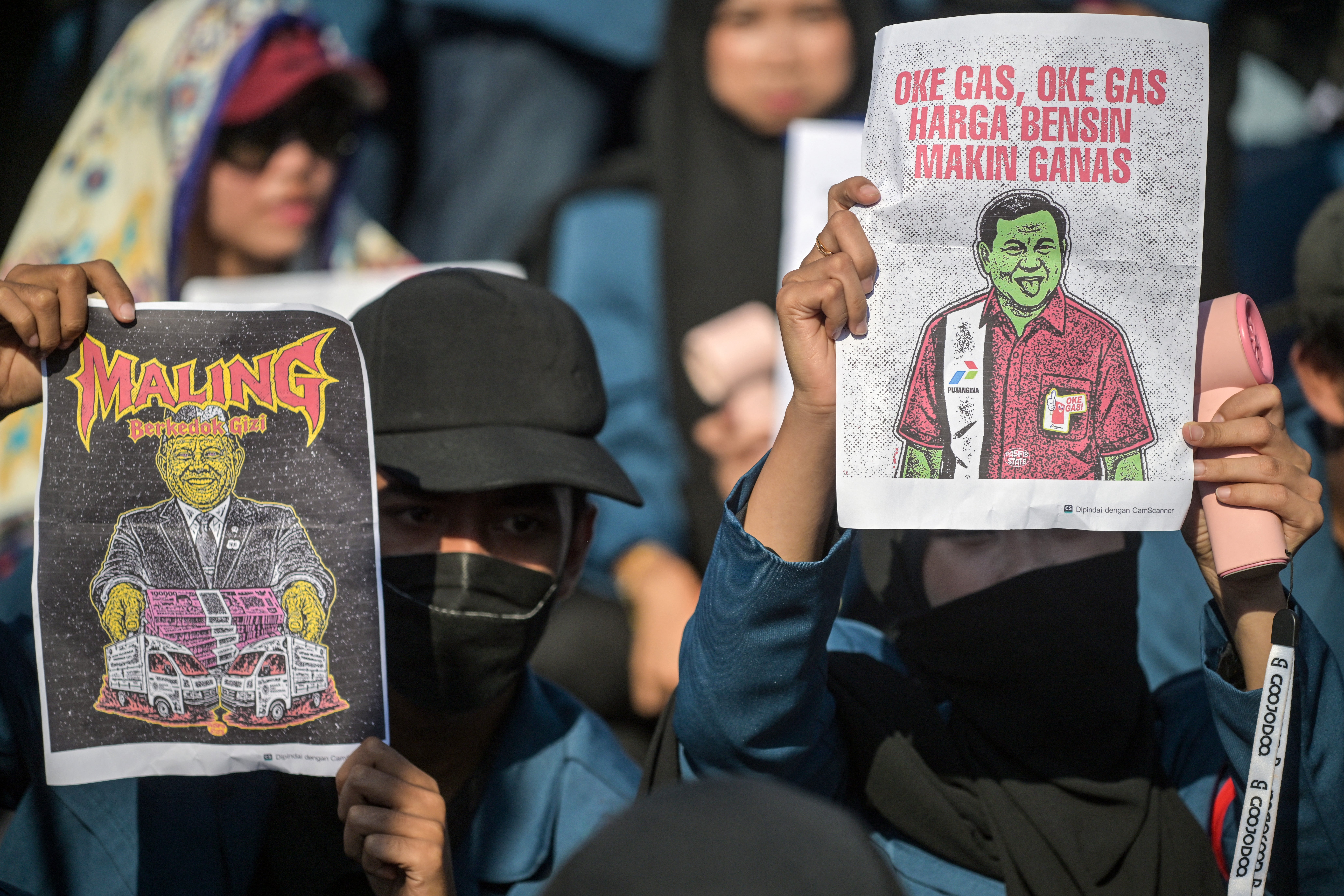 Students hold posters of president Prabowo Subianto, right, and the head of the National Nutrition Agency Dadan Hindayana, who was arrested on corruption charges, during a protest against a rise in non-subsidised fuel prices and the government's free school meals programme in Surabaya on 17 June 2026
