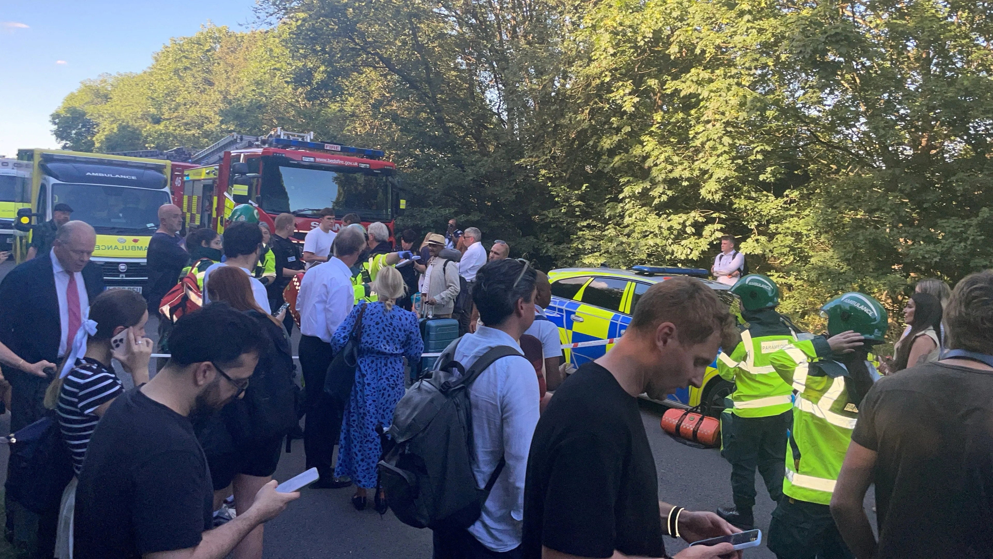 People and emergency service workers gather near the scene