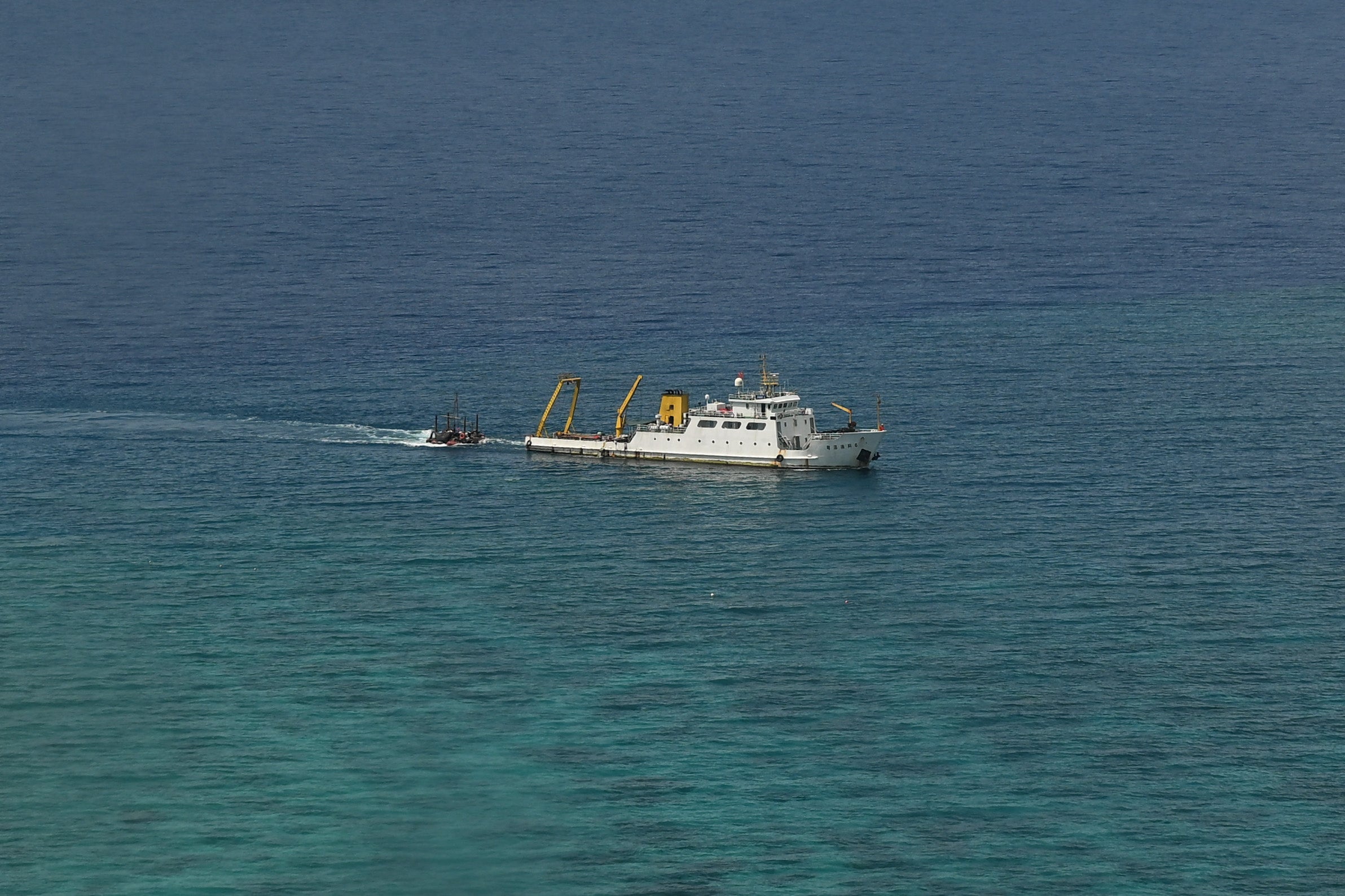 A ship identified by the Philippine Coast Guard as a Chinese research vessel is seen towing a floating structure at the mouth of Scarborough Shoal in the disputed South China Sea