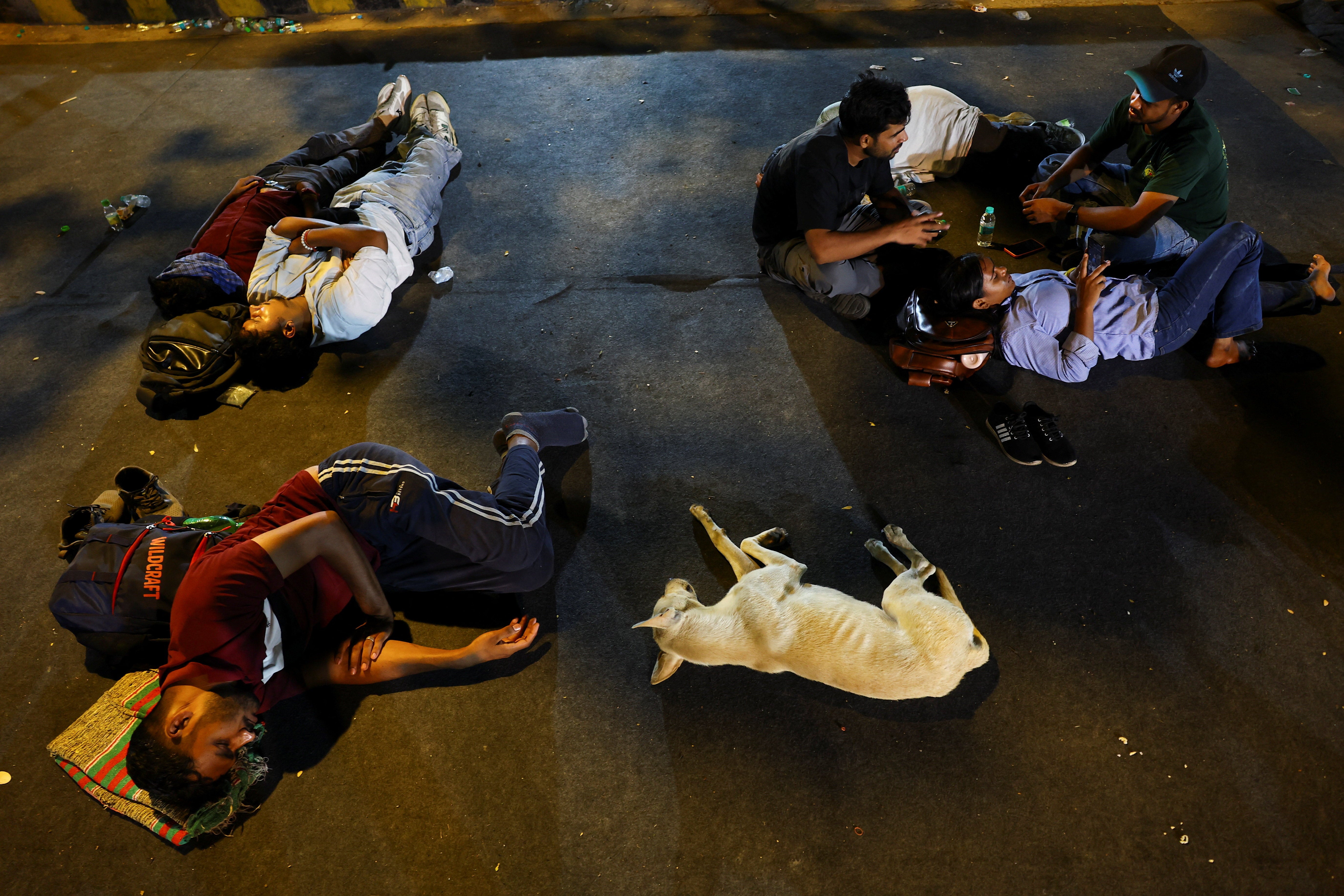 Supporters of the CJP sleep on a carpet laid on the road after spending the night at a New Delhi protest site