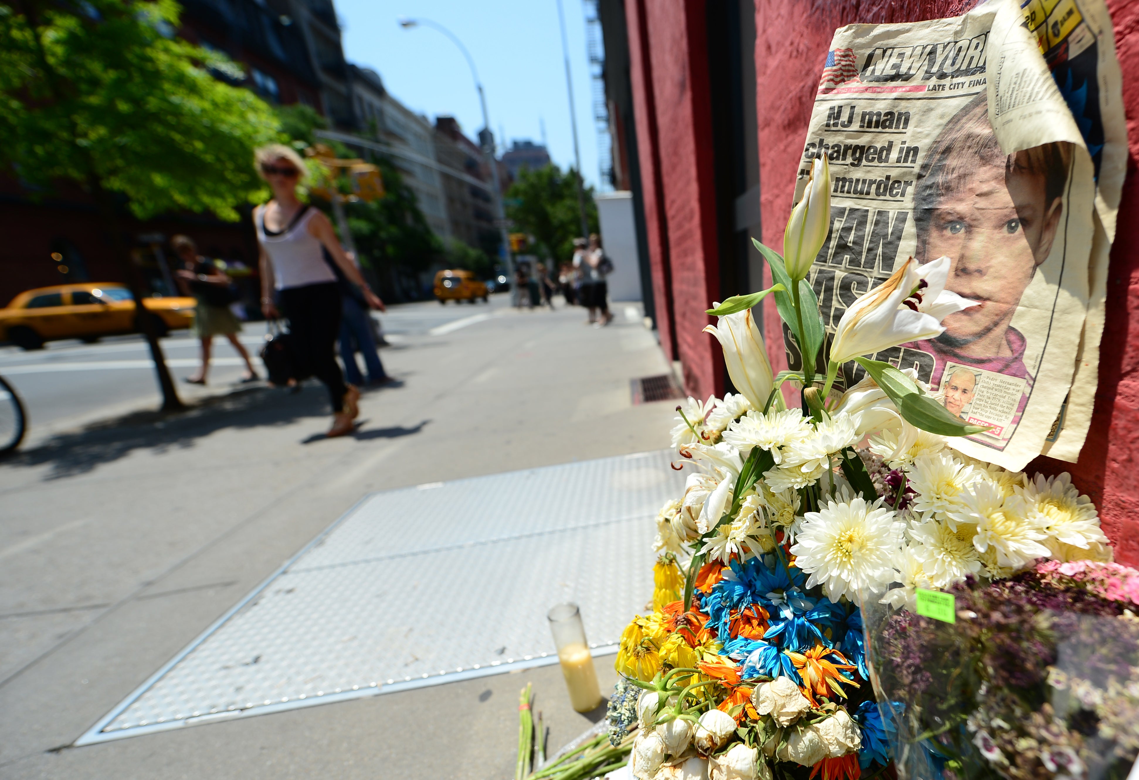 People walk past a street shrine to Etan Patz in front of the building where suspect Pedro Hernandez confessed to have strangled the boy