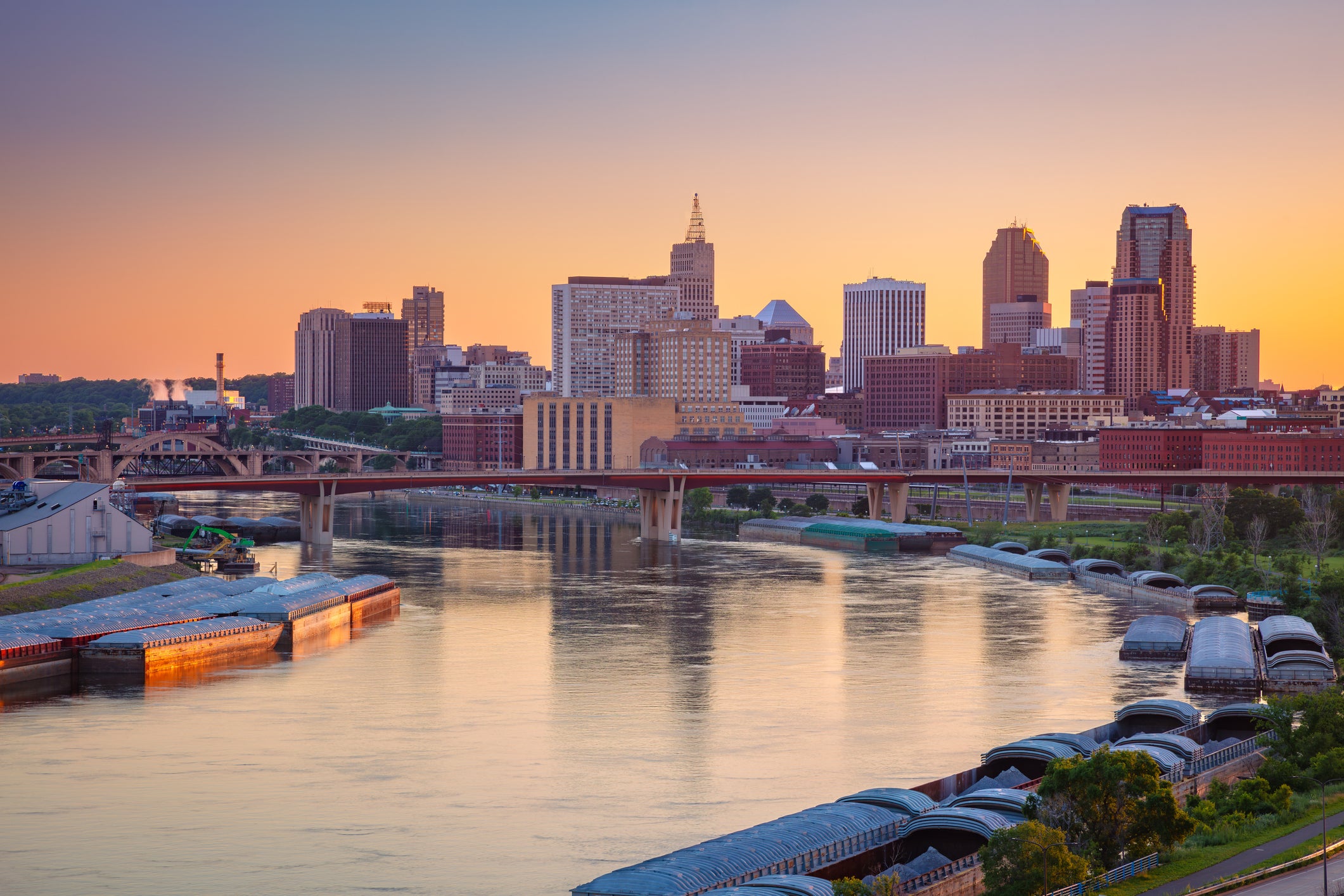 Aerial view of downtown St. Paul, Minnesota, featuring the skyline reflecting in the Mississippi River during a summer sunset.