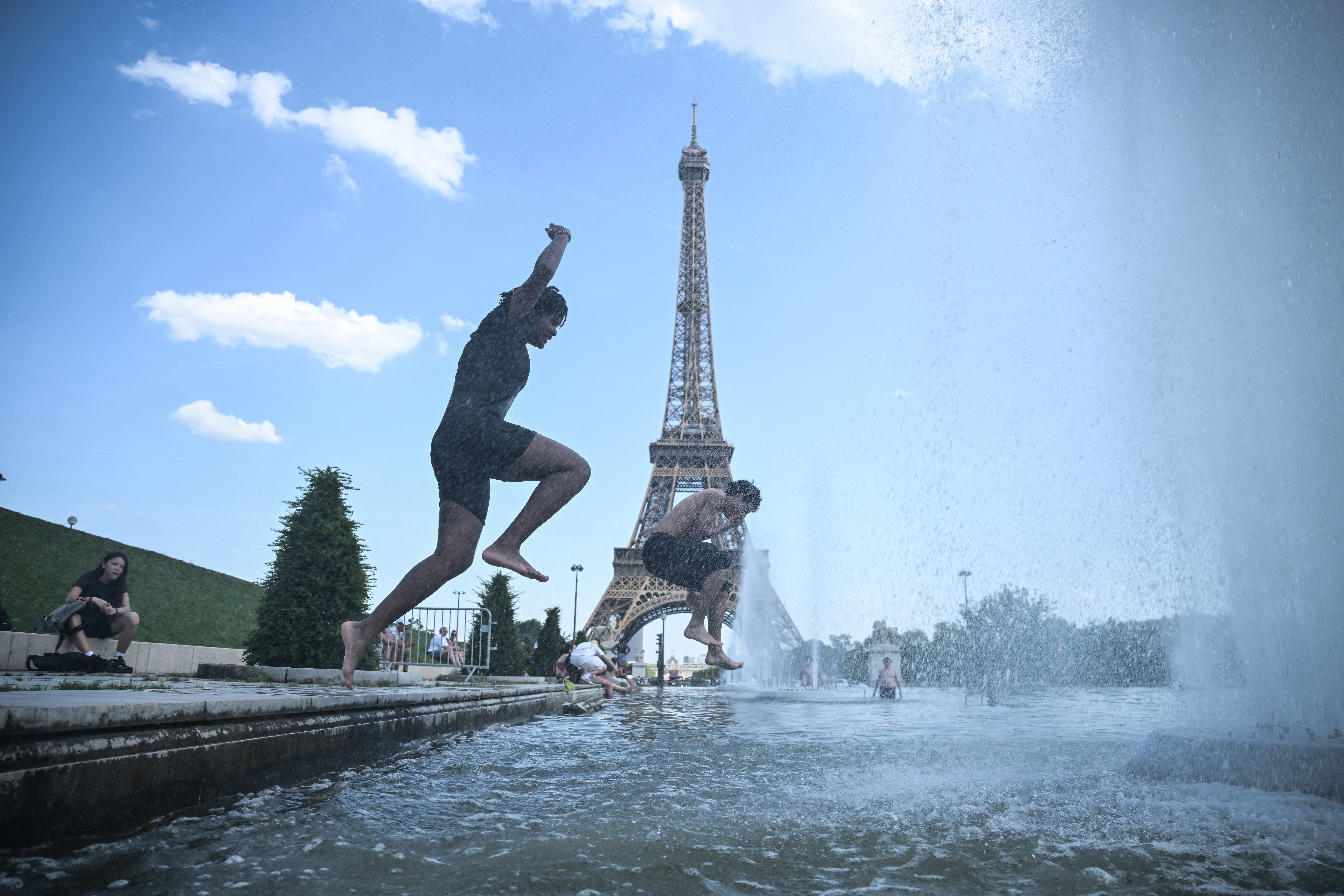 People jump in the Trocadero Fountain near the Eiffel Tower during a heatwave in Paris