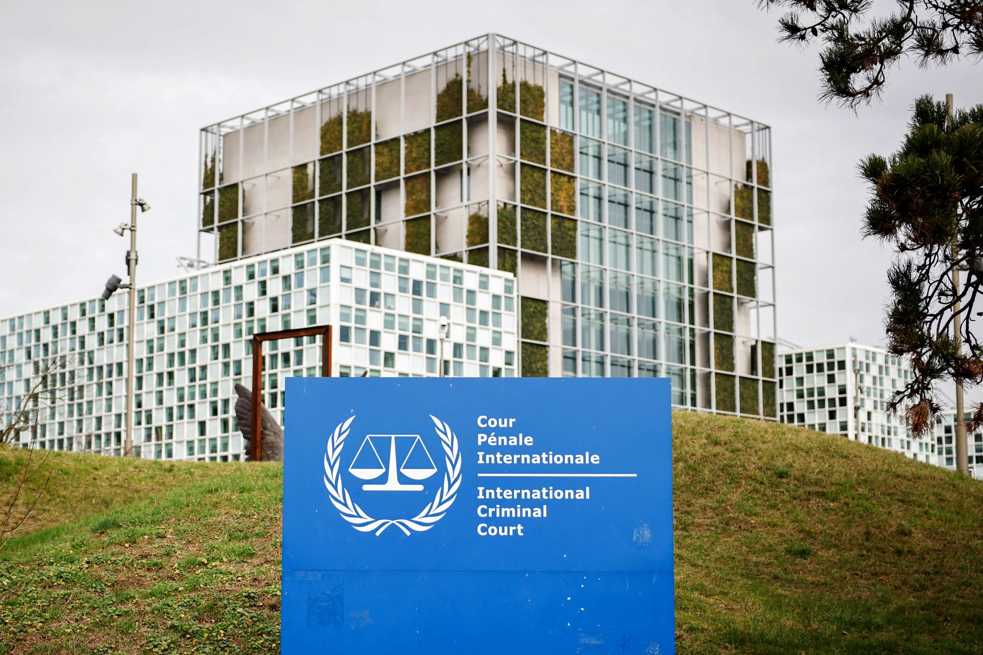 This photograph shows the "the International Criminal Court (ICC)" in the background with its logo on a sign in the foreground in The Hague