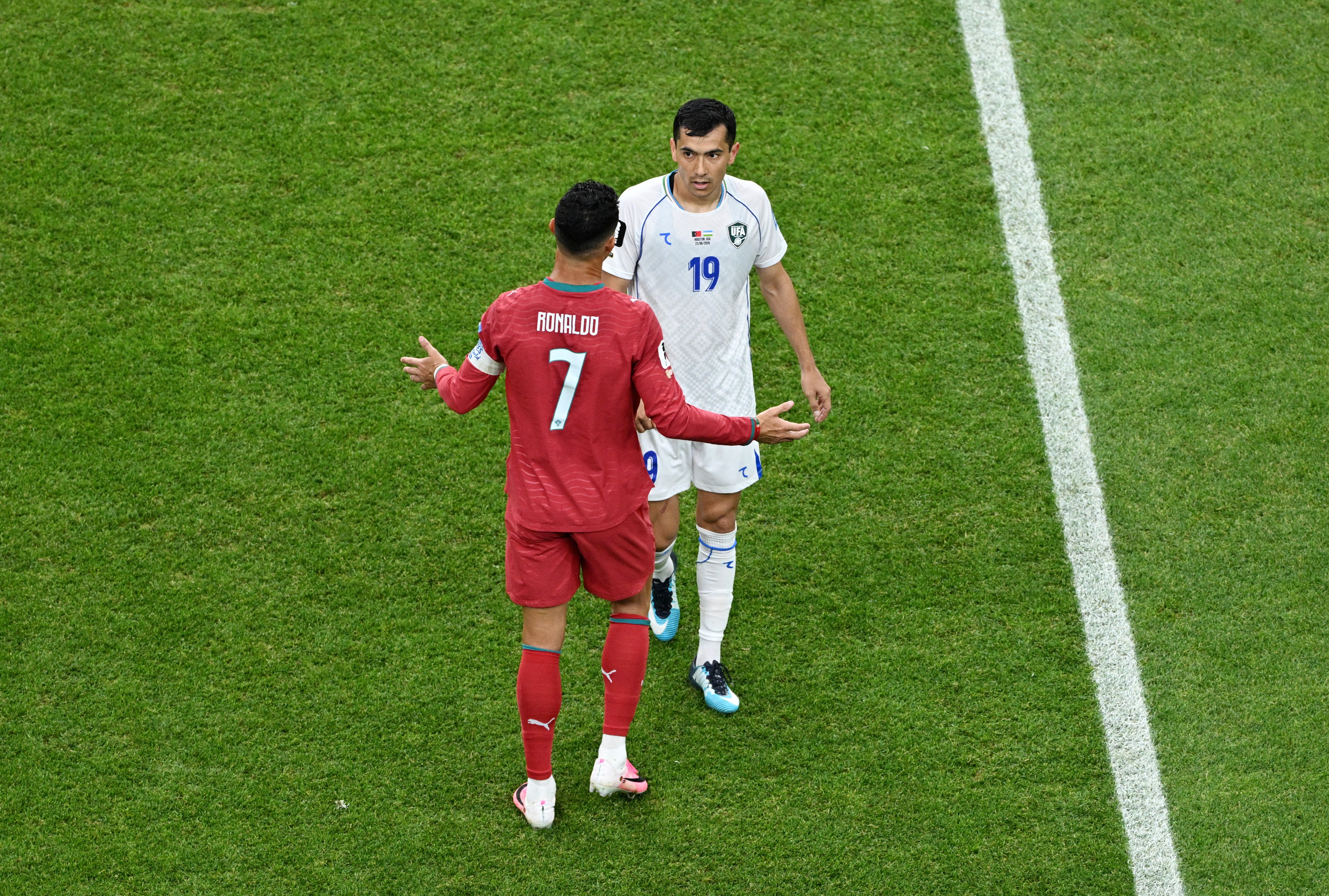 Uzbekistan's Azizjon Ganiev talks to Portugal's Cristiano Ronaldo after his goal was disallowed following a VAR review