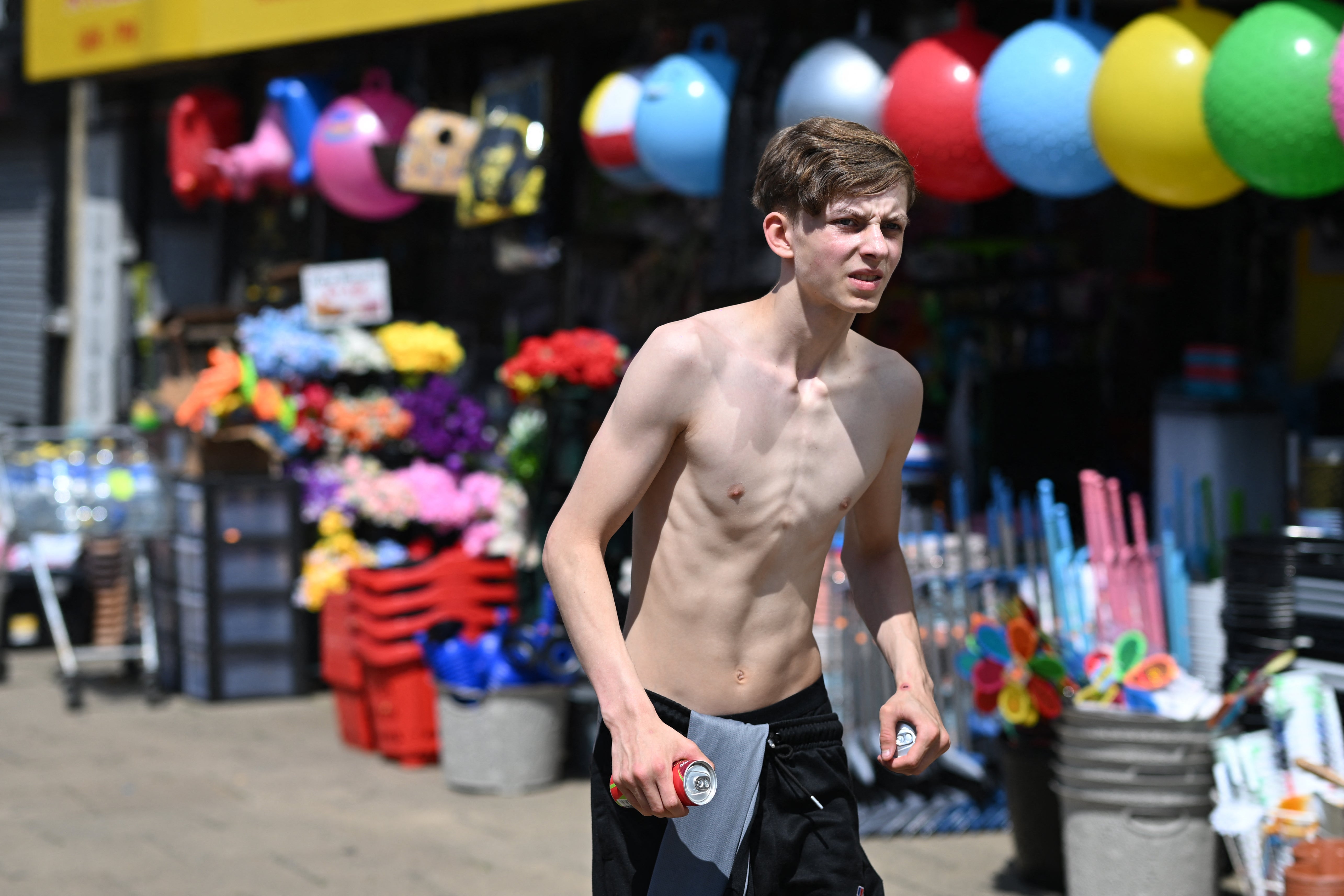 A pedestrian carries drinks in the sunshine in the town centre in Huddersfield in Northern England on 23 June 2026