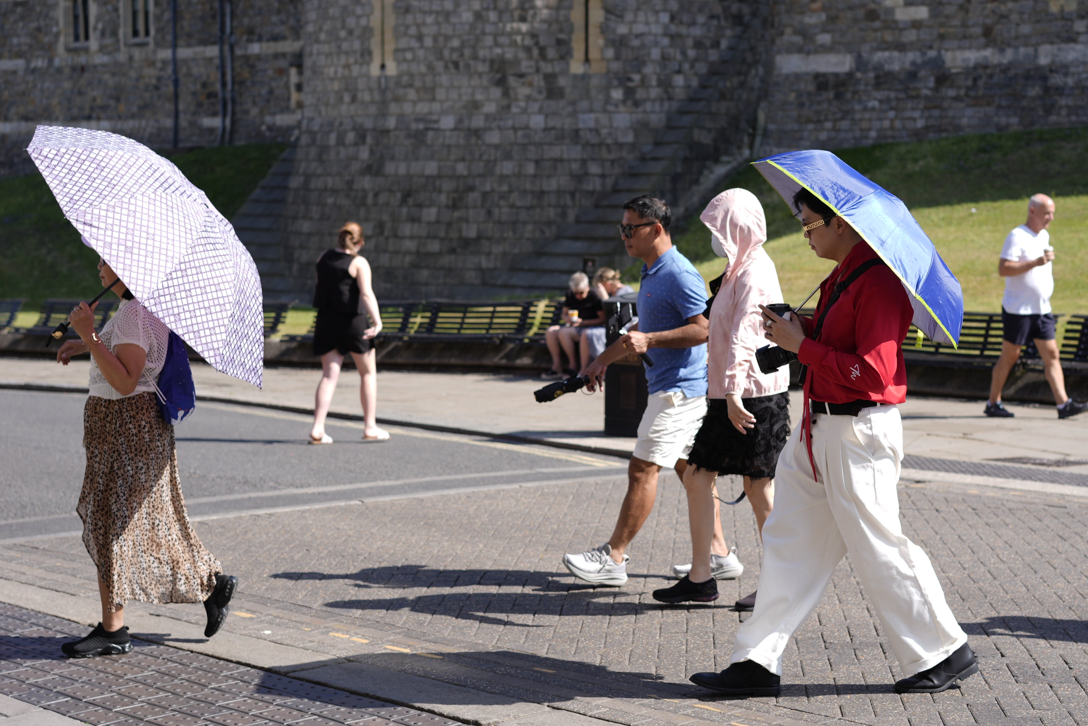 People use umbrellas to shade themselves from the sun in Windsor, Berkshire