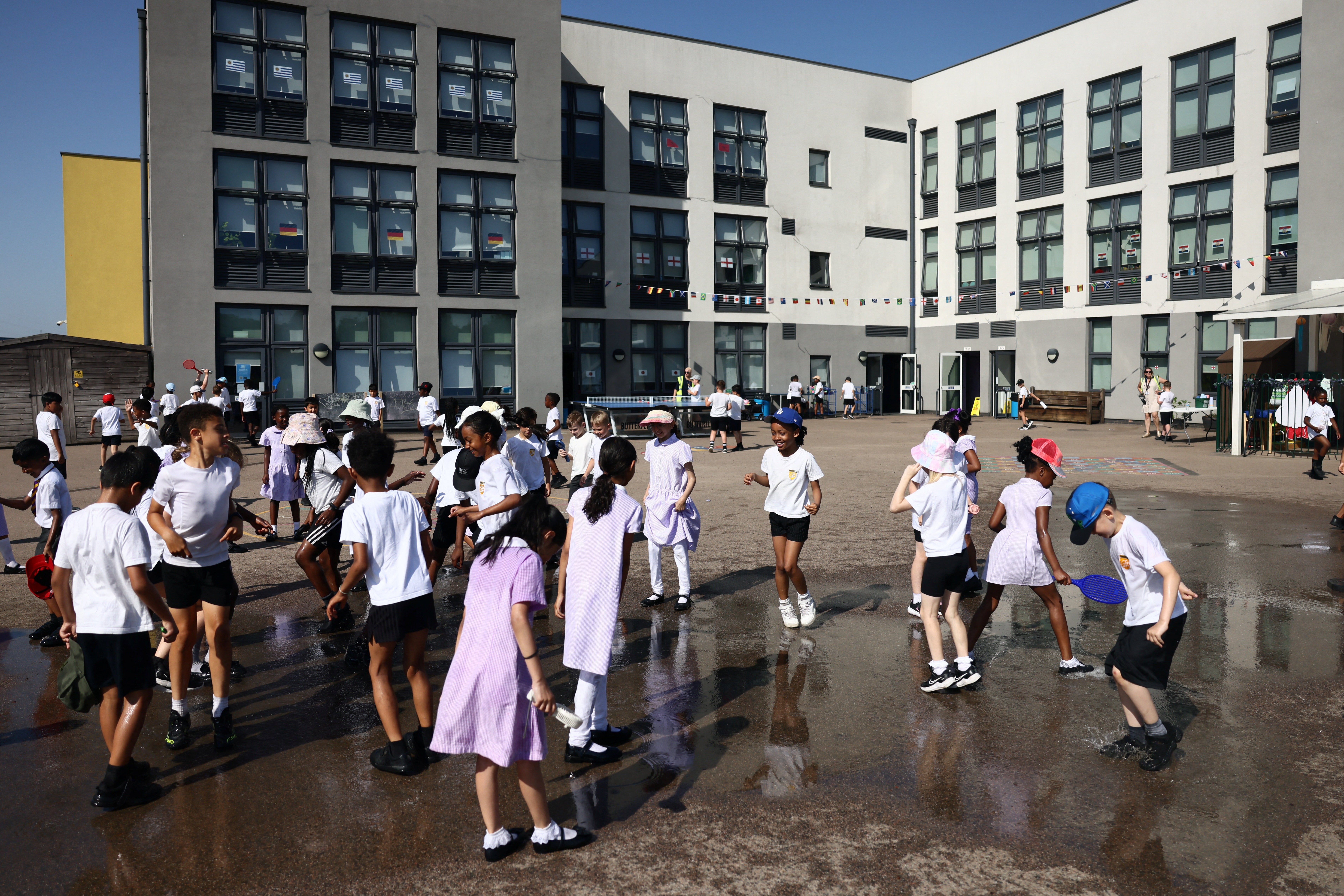 Pupils play outside after water play at the Harris Academy Primary Mayflower school (Reuters)