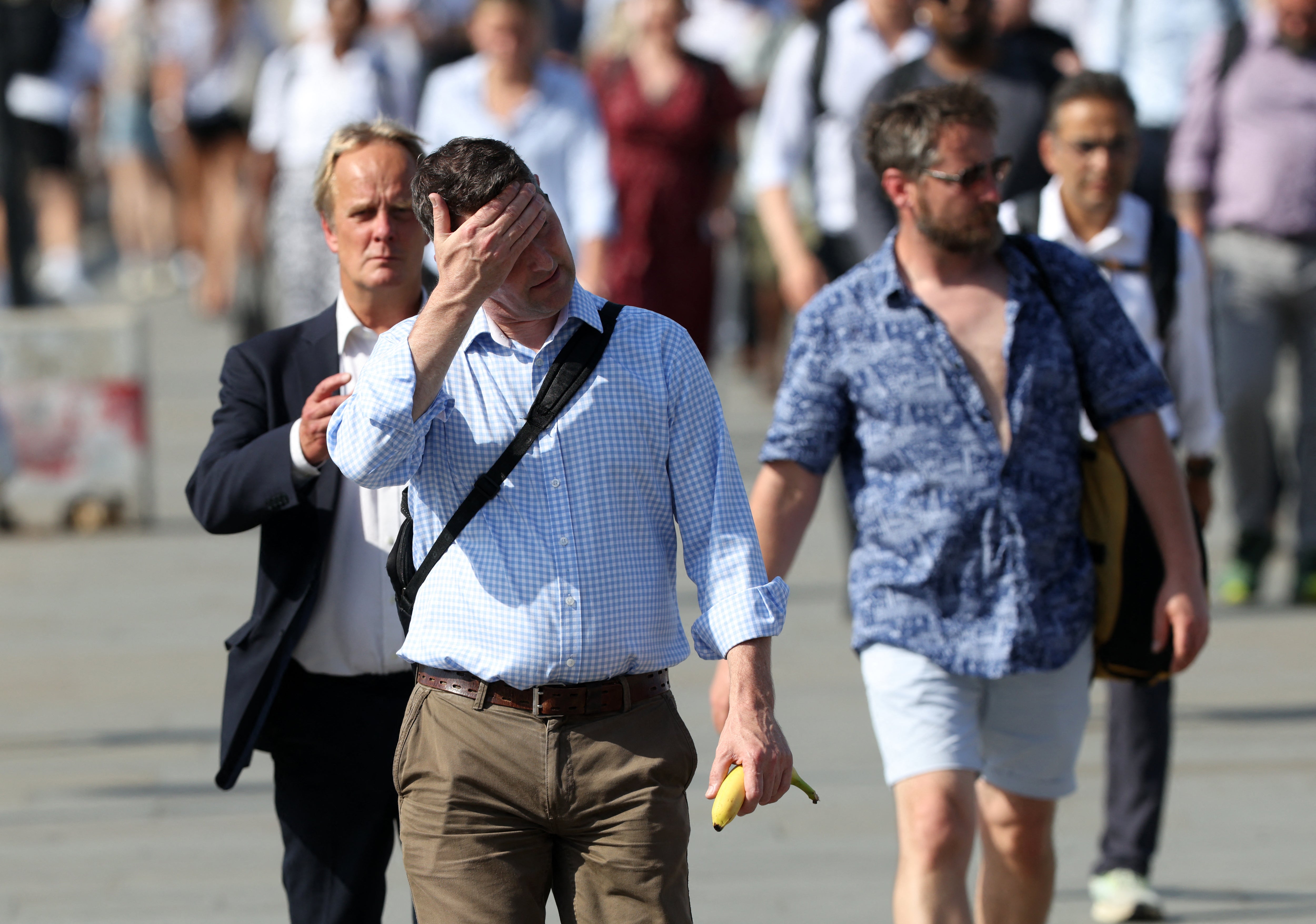 Commuters walk in the sun as they cross London Bridge