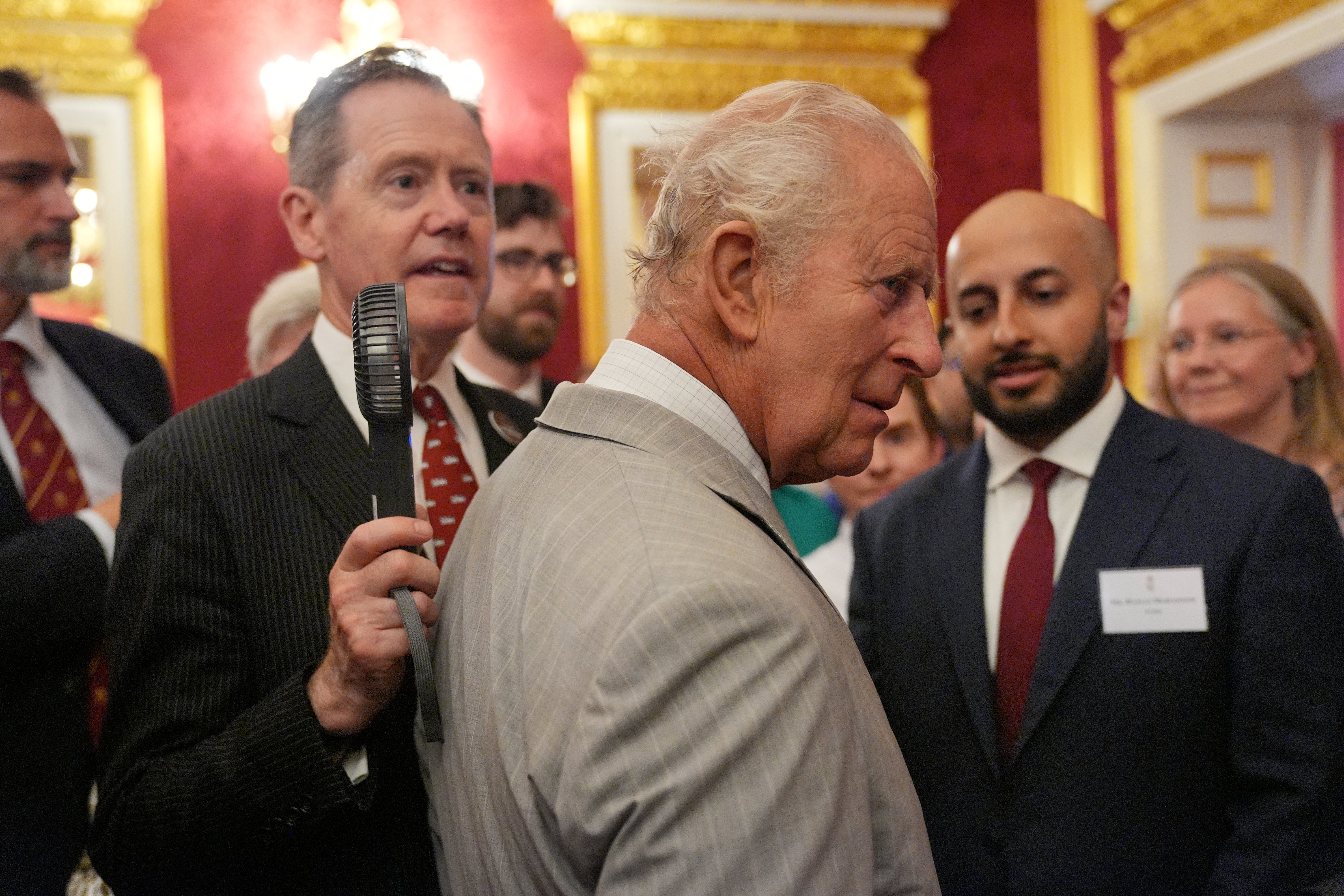 An aide held a fan close to Charles as he met guests at the event (Yui Mok/PA)