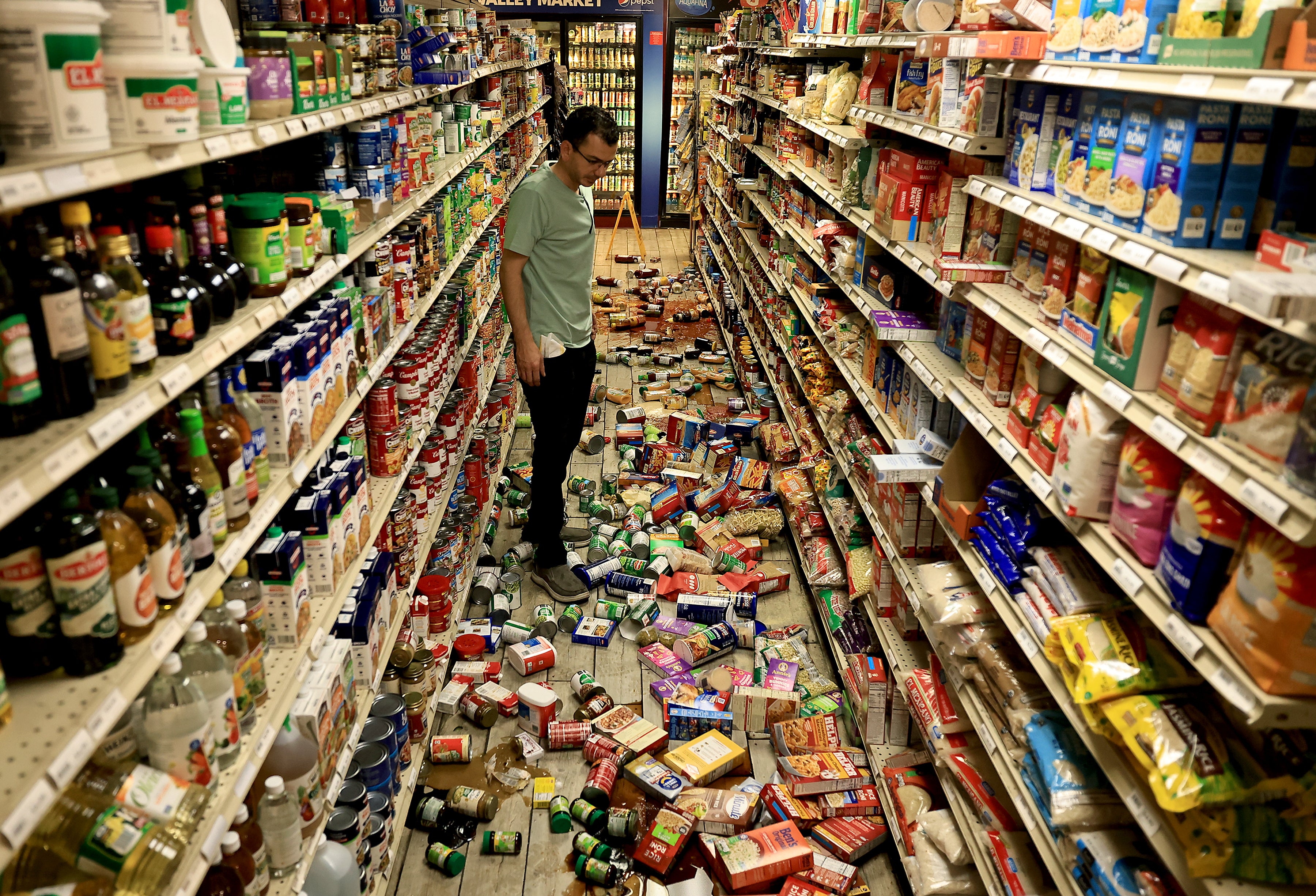 Redwood Valley Market owner Alex Chehada looks at items which fell off the shelves after an earthquake in Redwood Valley