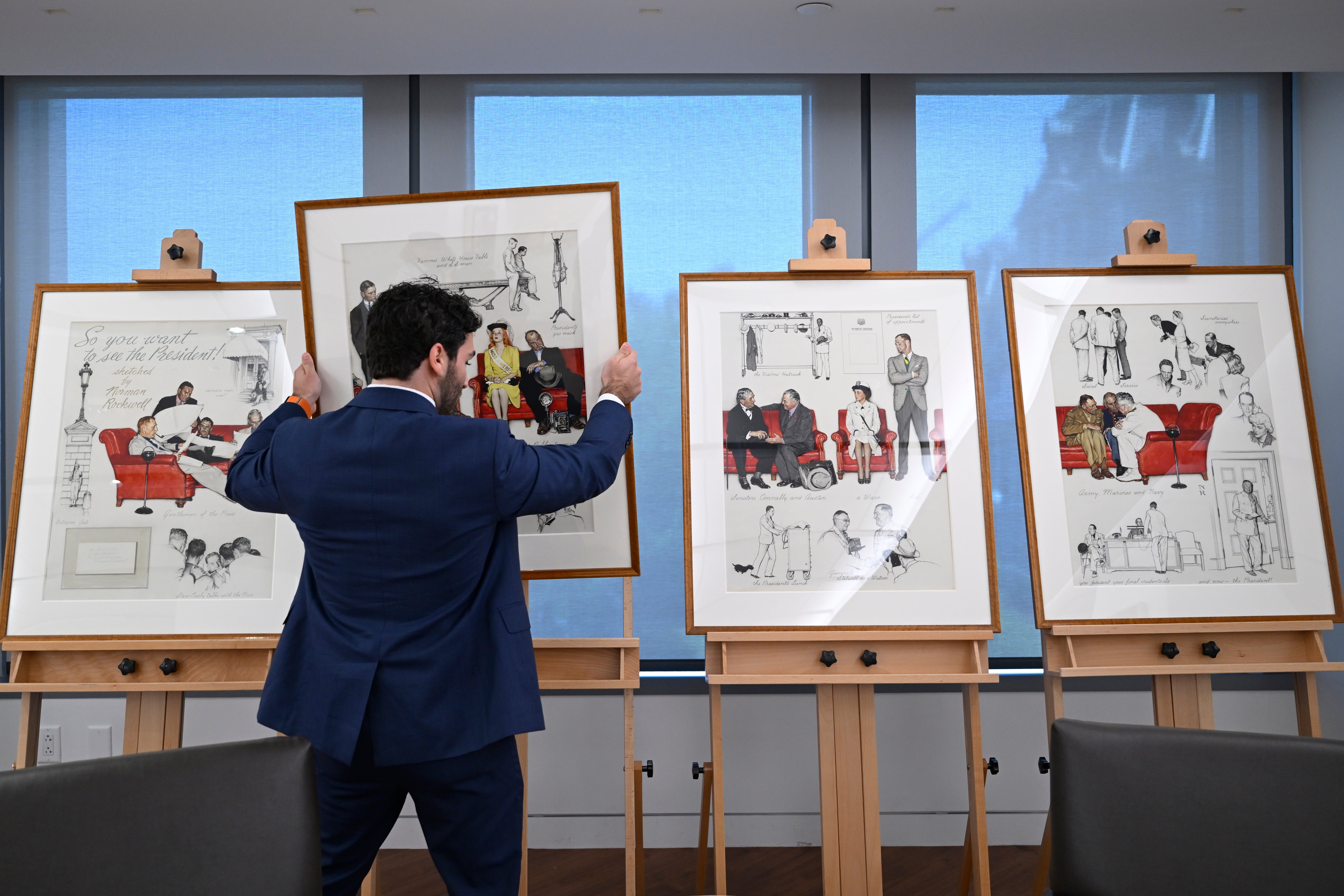 <p>Luke Boorady, of the White House Historical Association, arranges a suite of four interrelated paintings by Norman Rockwell titled, ‘So You Want to See the President!’</p>