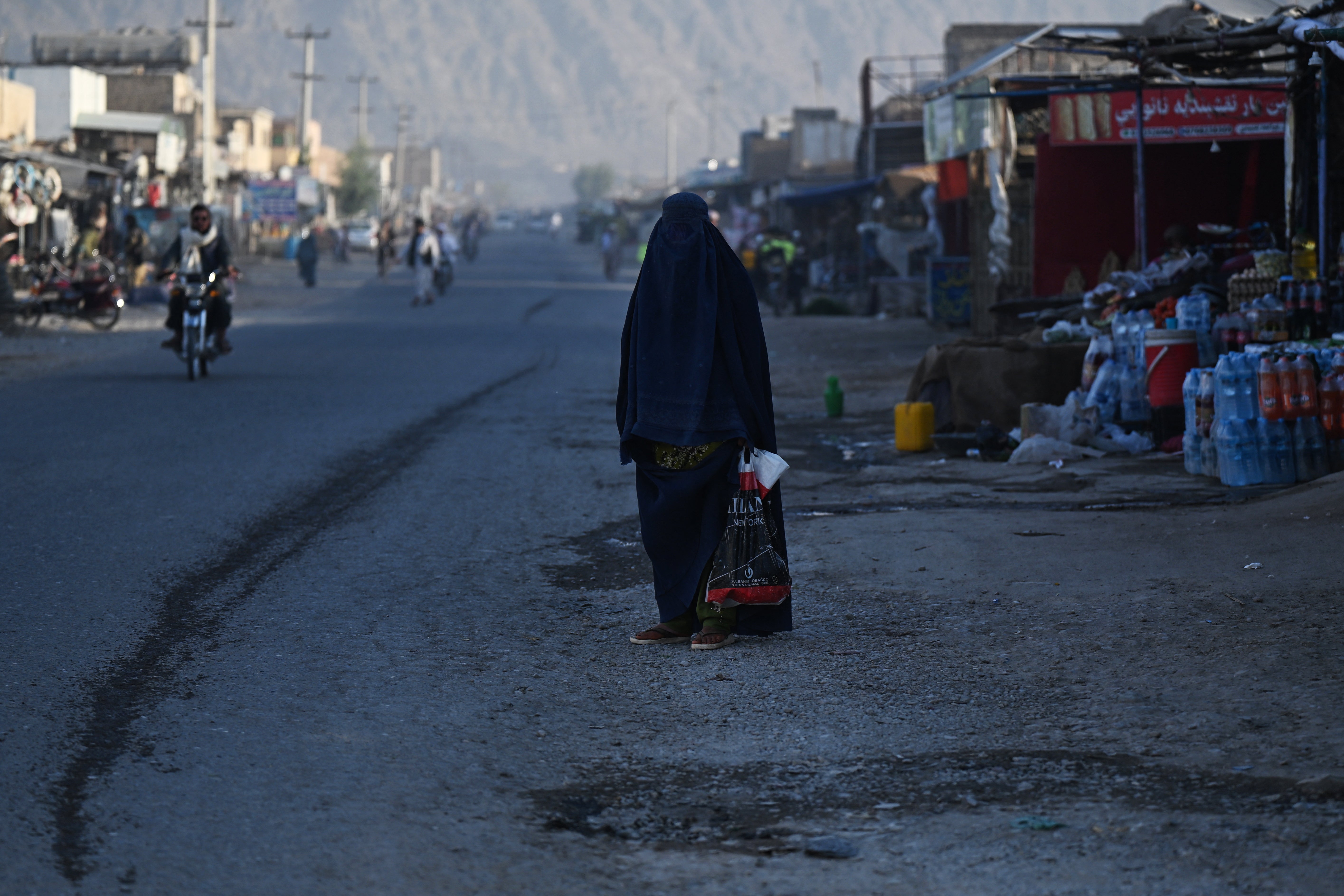 An Afghan burqa-clad woman waits for a taxi along a street at a village in Kandahar (AFP/Getty)