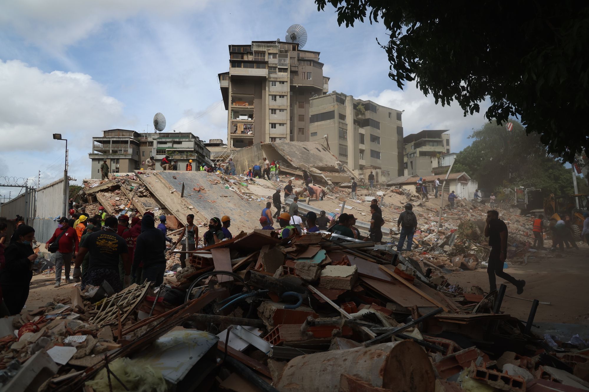 People and rescuers work on the debris from the Moises building on Avenida Anauco