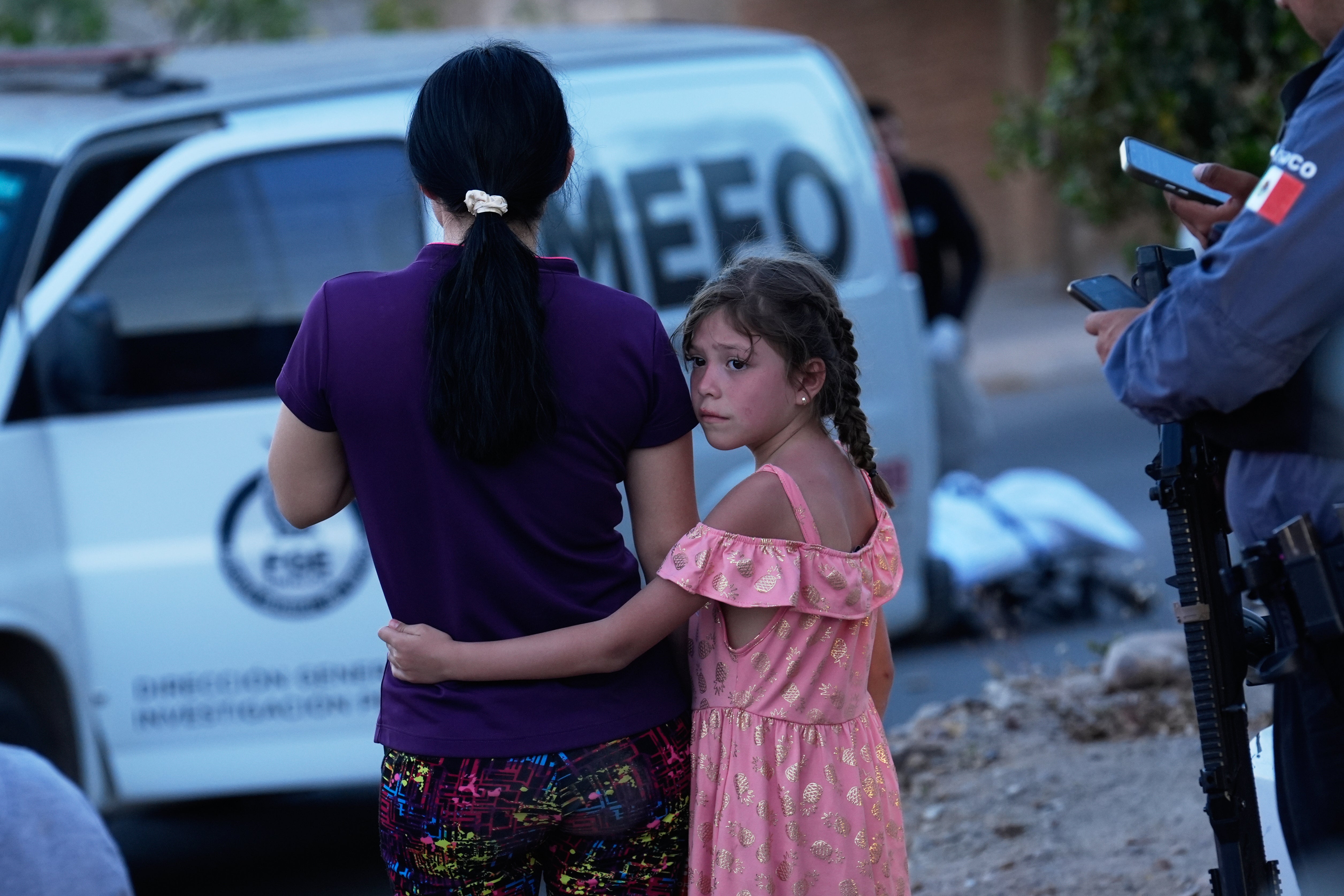 Relatives of a victim of a fatal armed attack look on as forensic workers investigate the scene, in Culiacán, Sinaloa state, Mexico