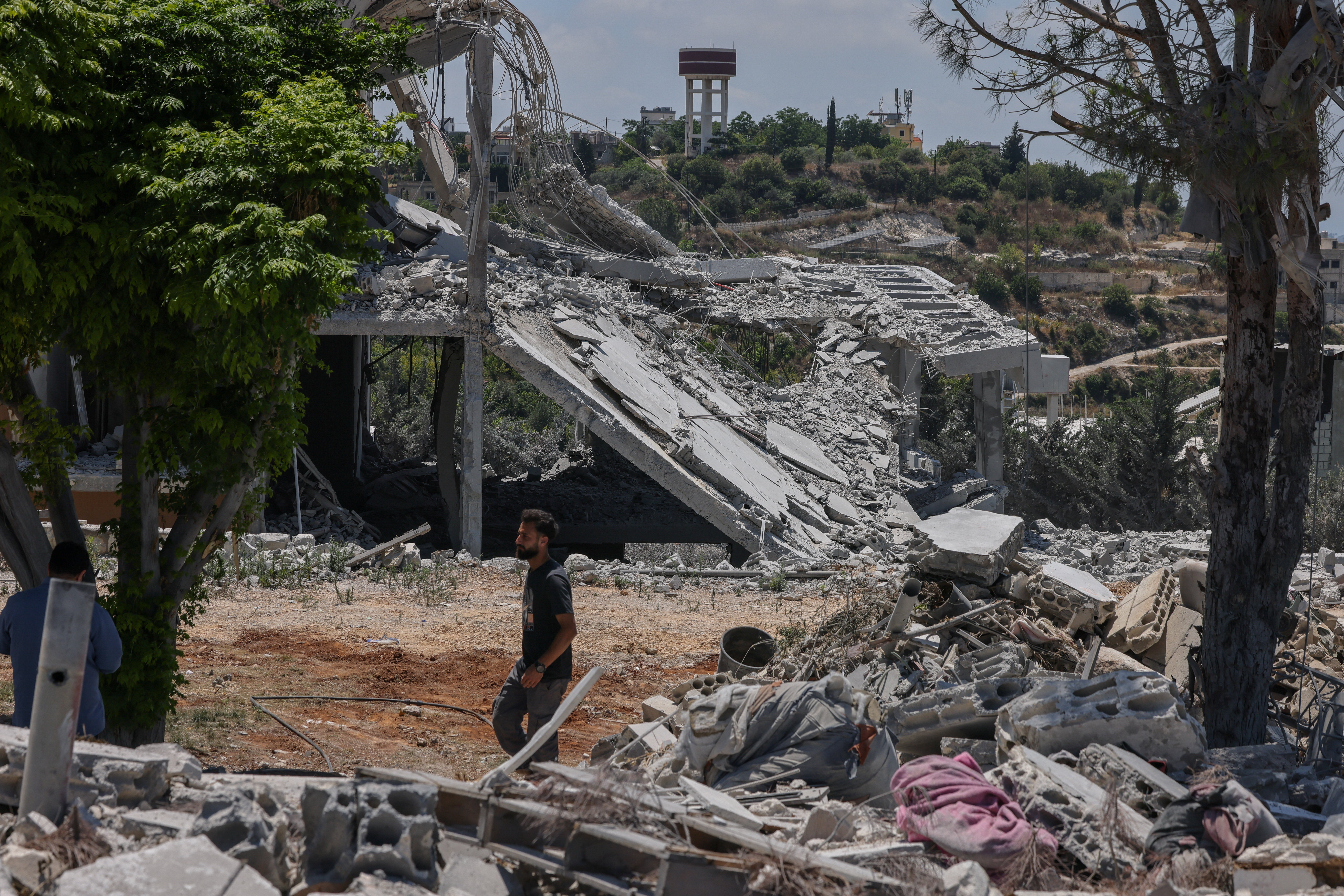 Hadi Hussein, a municipal worker who said he did not leave the village during the war, walks by houses destroyed in an Israeli airstrike in Tyre, on 25 June