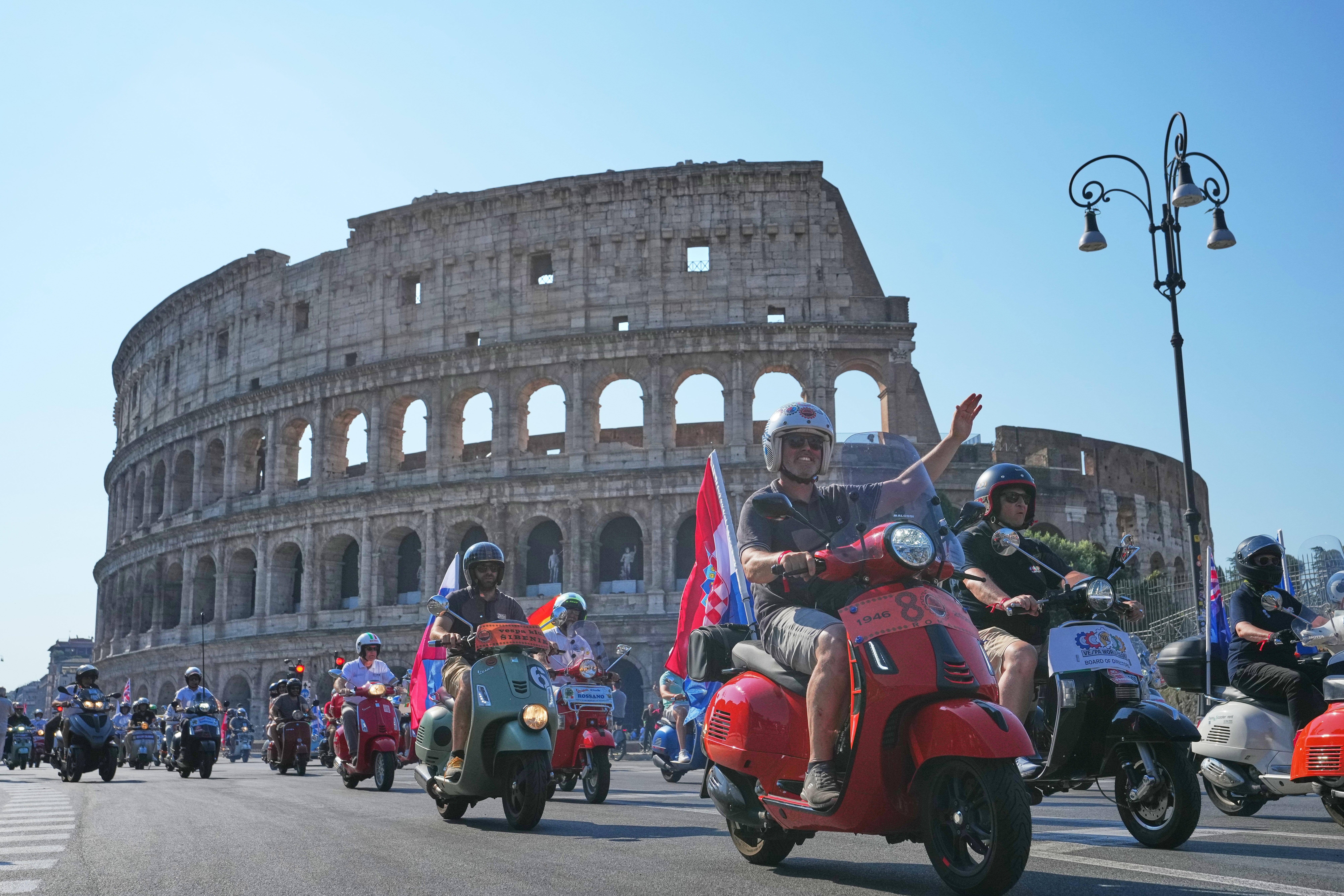 Vespa enthusiasts parade in front of the Colosseum during celebrations for the 80th anniversary of the Vespa scooter, in Rome, Saturday, June 27, 2026. (AP Photo/Alessandra Tarantino)