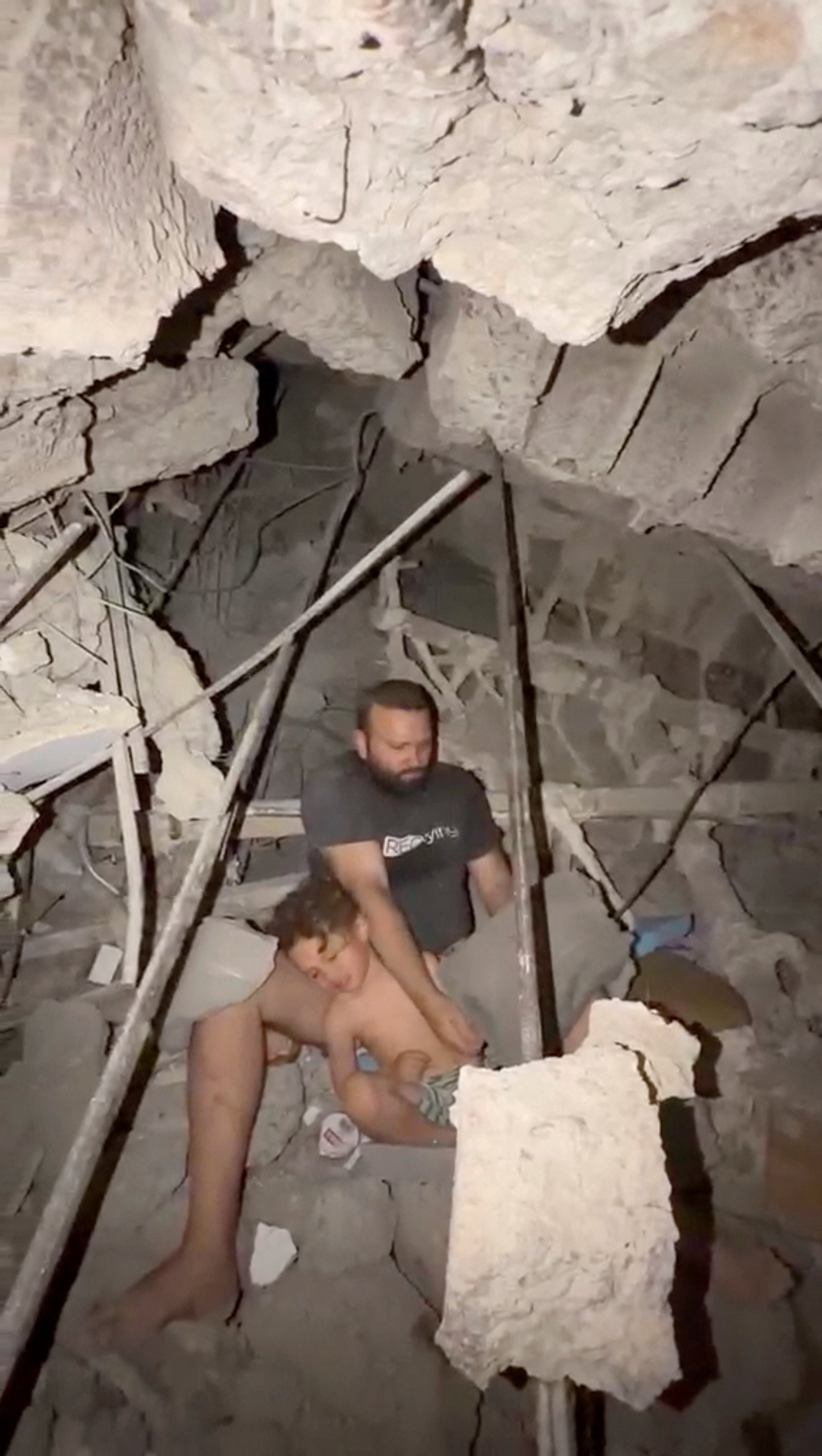 Jofram Gallipoli and his son sit under the rubble of their La Guaira building on Thursday