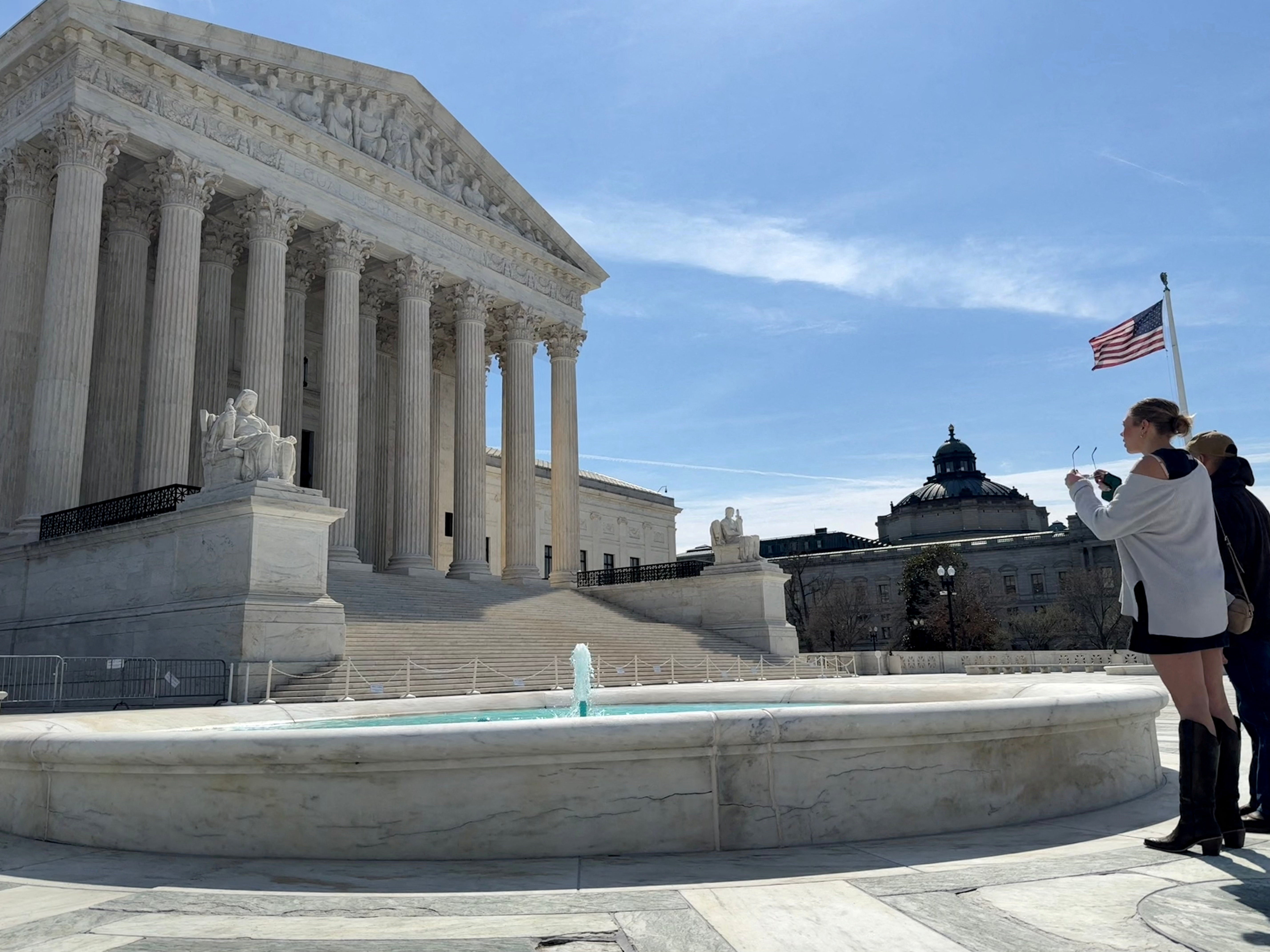 People look at the U.S. Supreme Court building in Washington, D.C., March 14, 2026. REUTERS/Will Dunham/File Photo