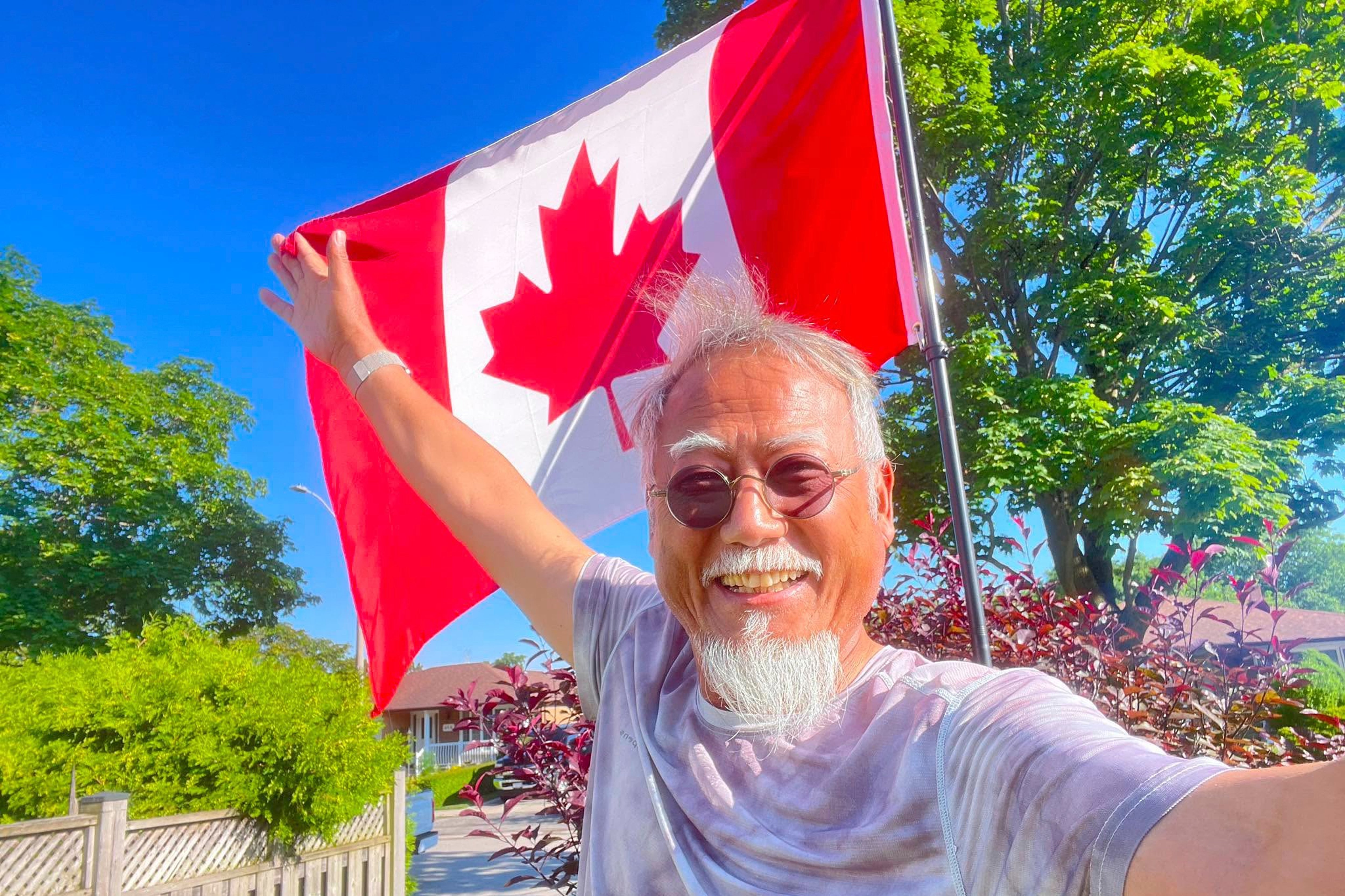 Dong Guangping poses for a photo with the Canadian flag after arriving in Toronto, Canada, on June 27, 2026