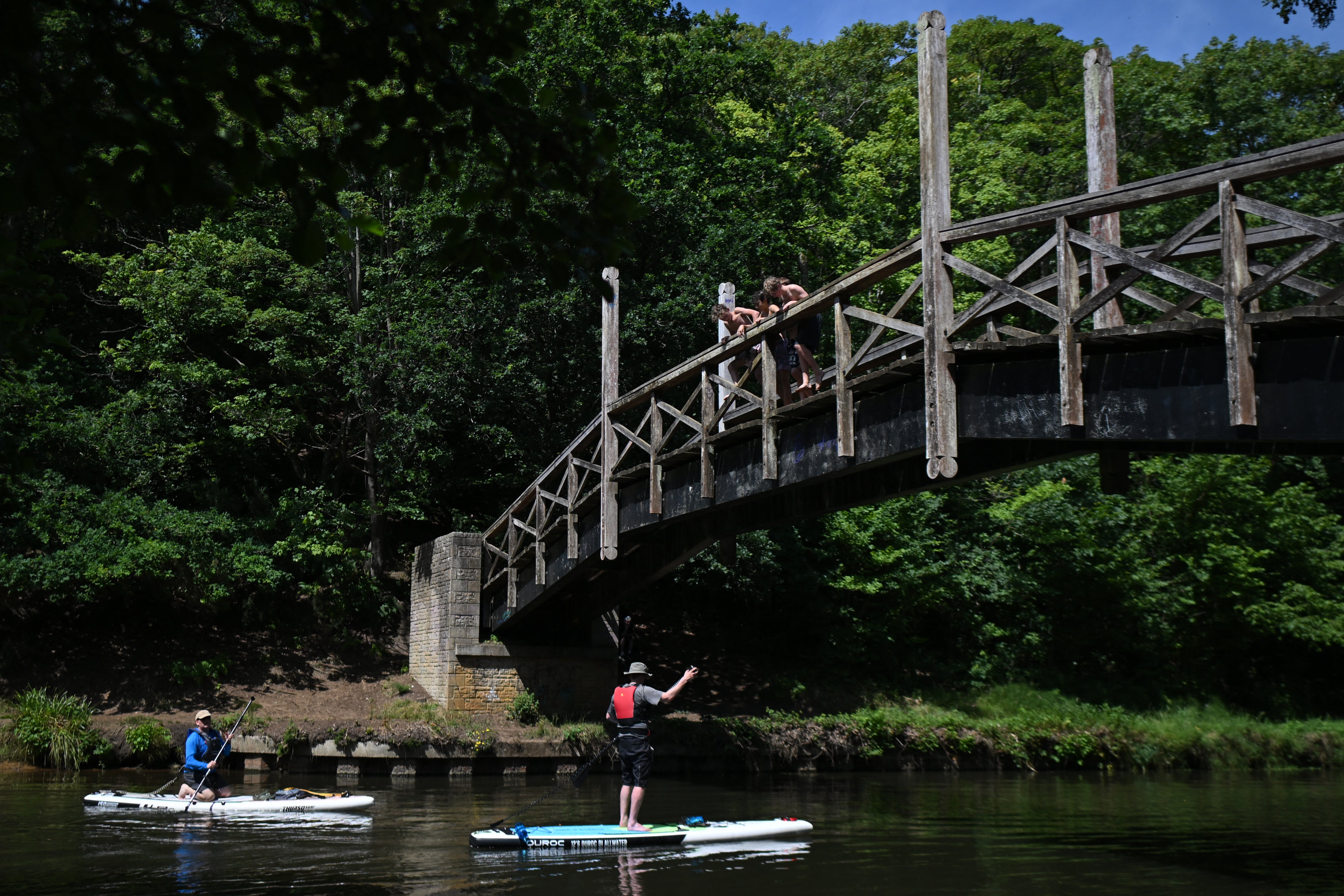Paddleboarders pass under a bridge over the River Wey near Guildford amid rising temperatures