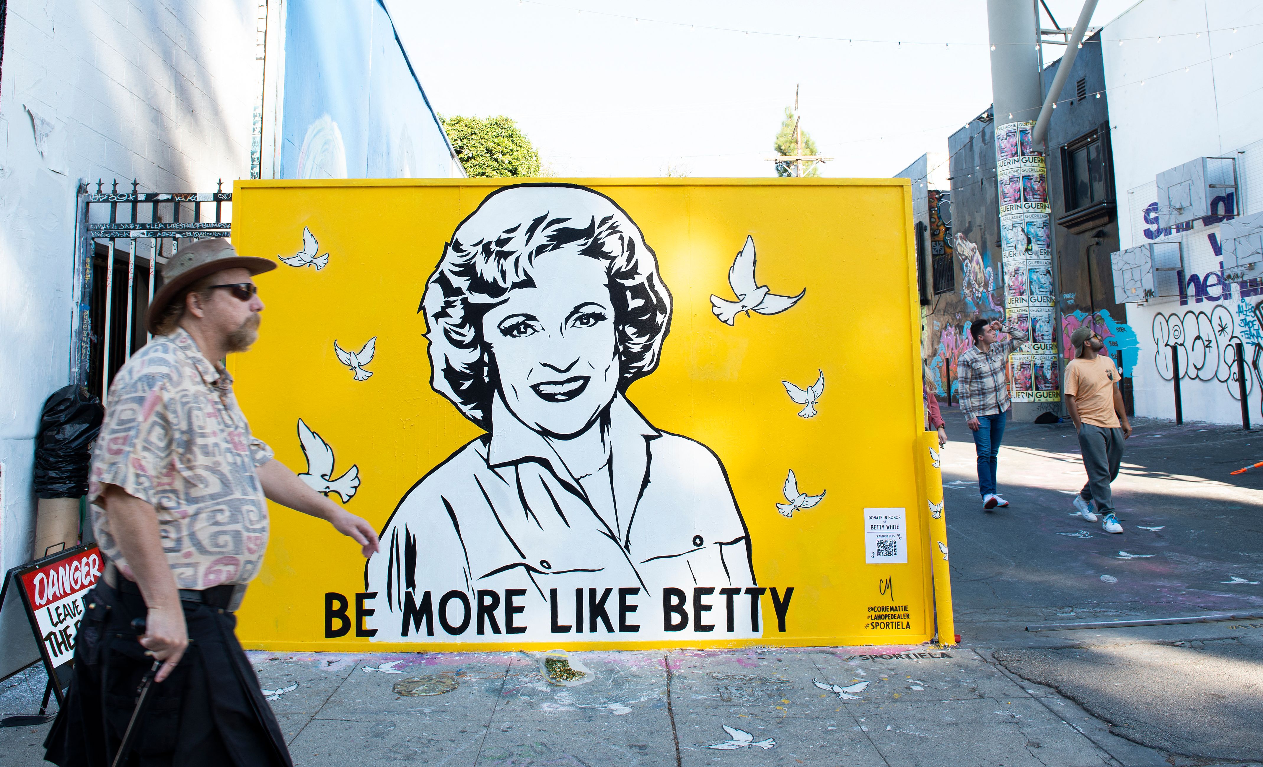 A person walks by street artist Corie Mattie's 