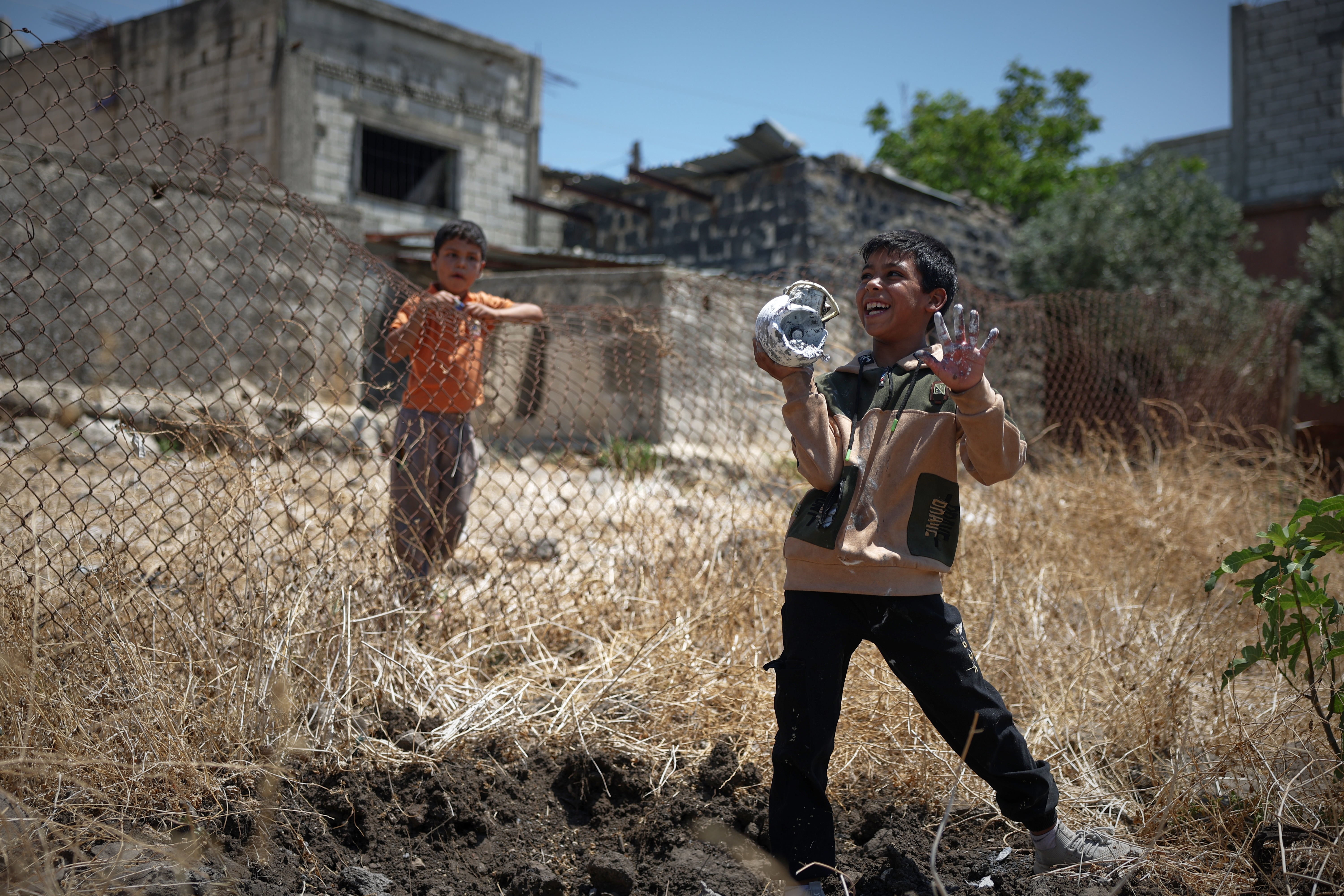 A local boy plays with the remains of an exploded Israeli shell as another boy looks on in the village of Abdin, Daraa province, Syria, Monday, June 29, 2026. (AP Photo/Ghaith Alsayed) (Ghaith Alsayed)