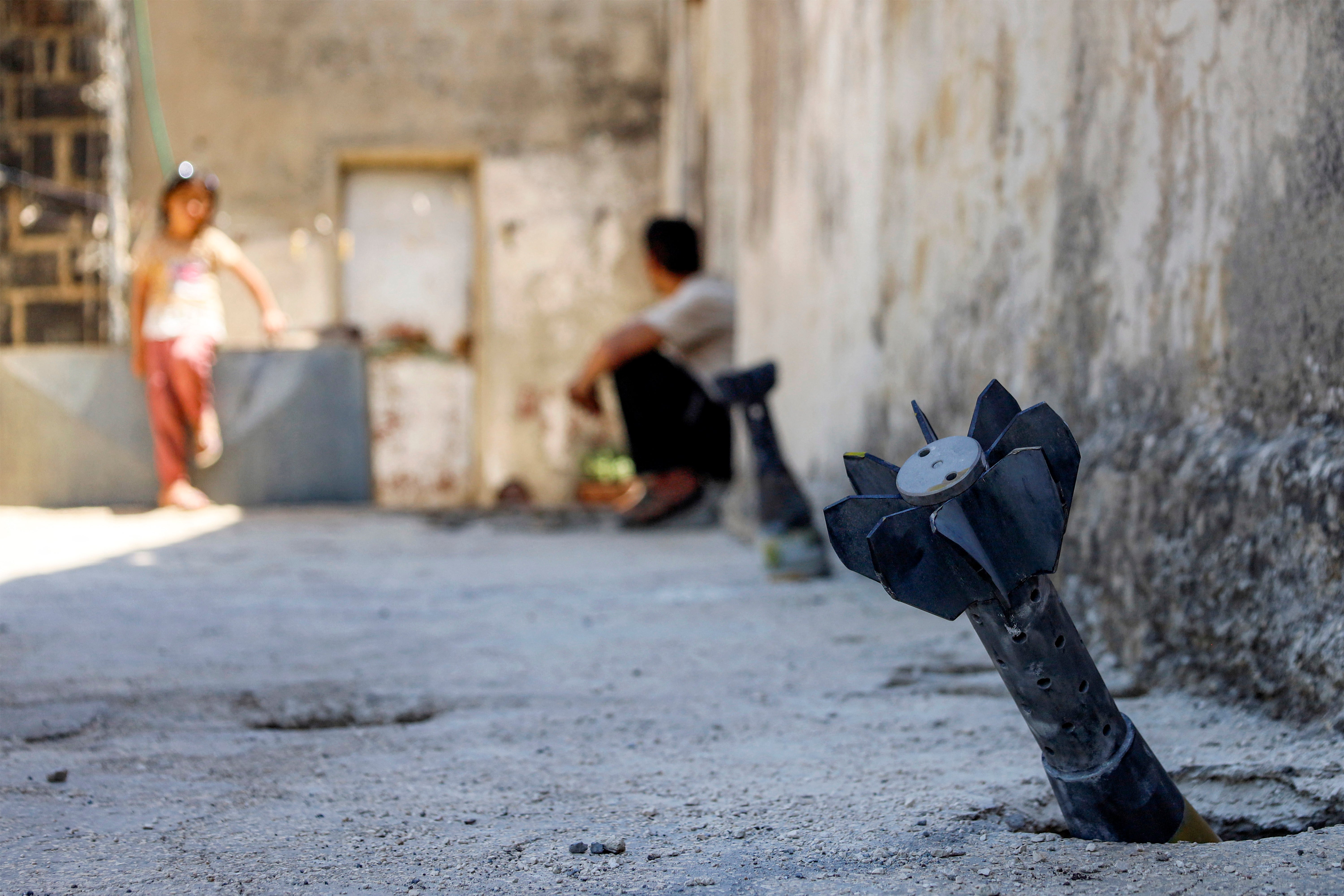 A man speaks with a child while sitting near an unexploded artillery shell that fell during reported overnight Israeli bombardment that hit the village of Abidin in Syria's southwestern Daraa province, close to the Golan Heights, on June 29, 2026. (AFP/Getty)
