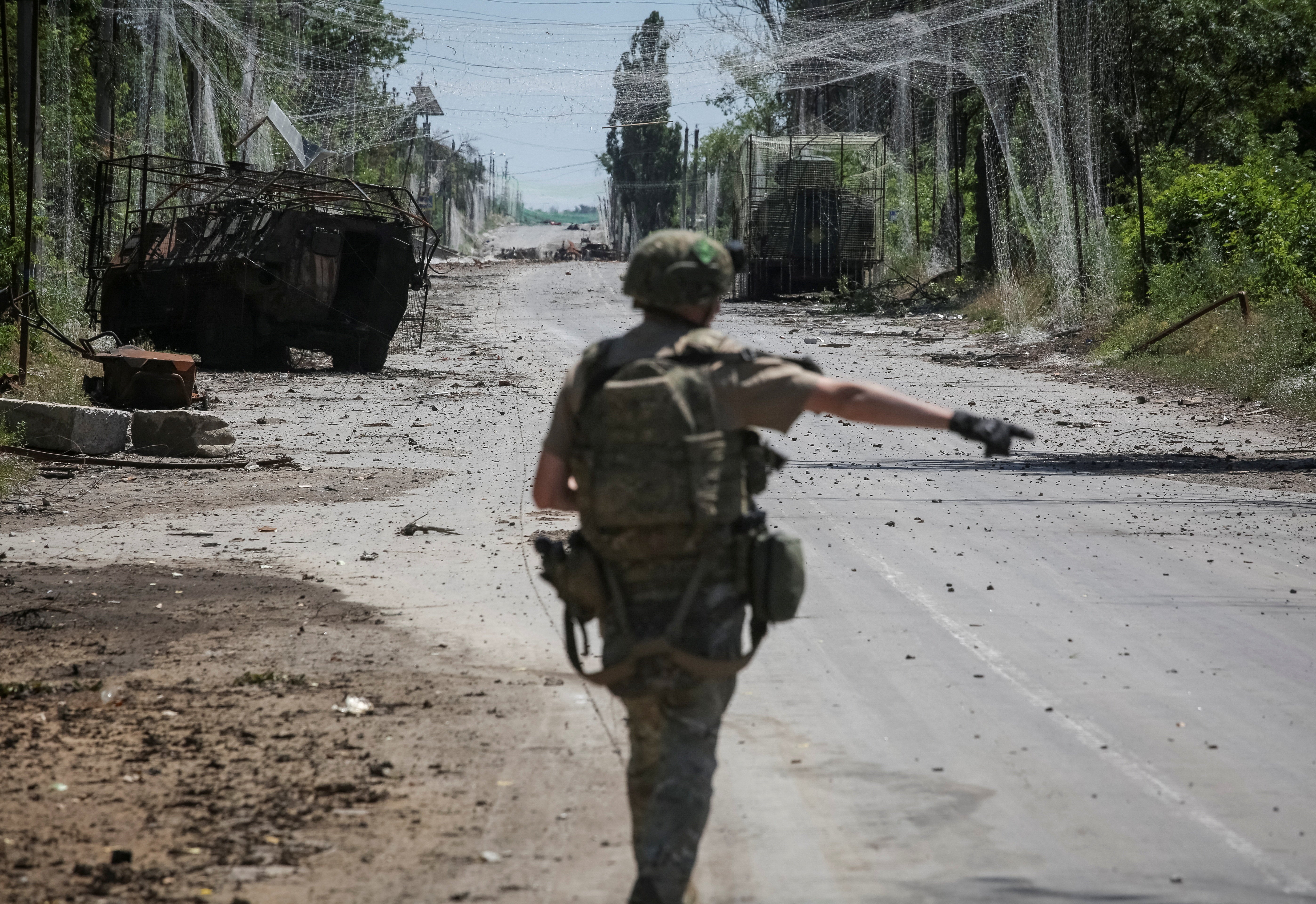 A serviceman of the consolidated Brigade 'Khyzhak' of the Ukrainian Patrol Police Department walks along a road near anti-drone nets and destroyed military vehicles as he takes part in a mission to protect a road from Russian drones between frontline towns of Druzhkivka and Kostiantynivka in Donetsk region (Reuters)