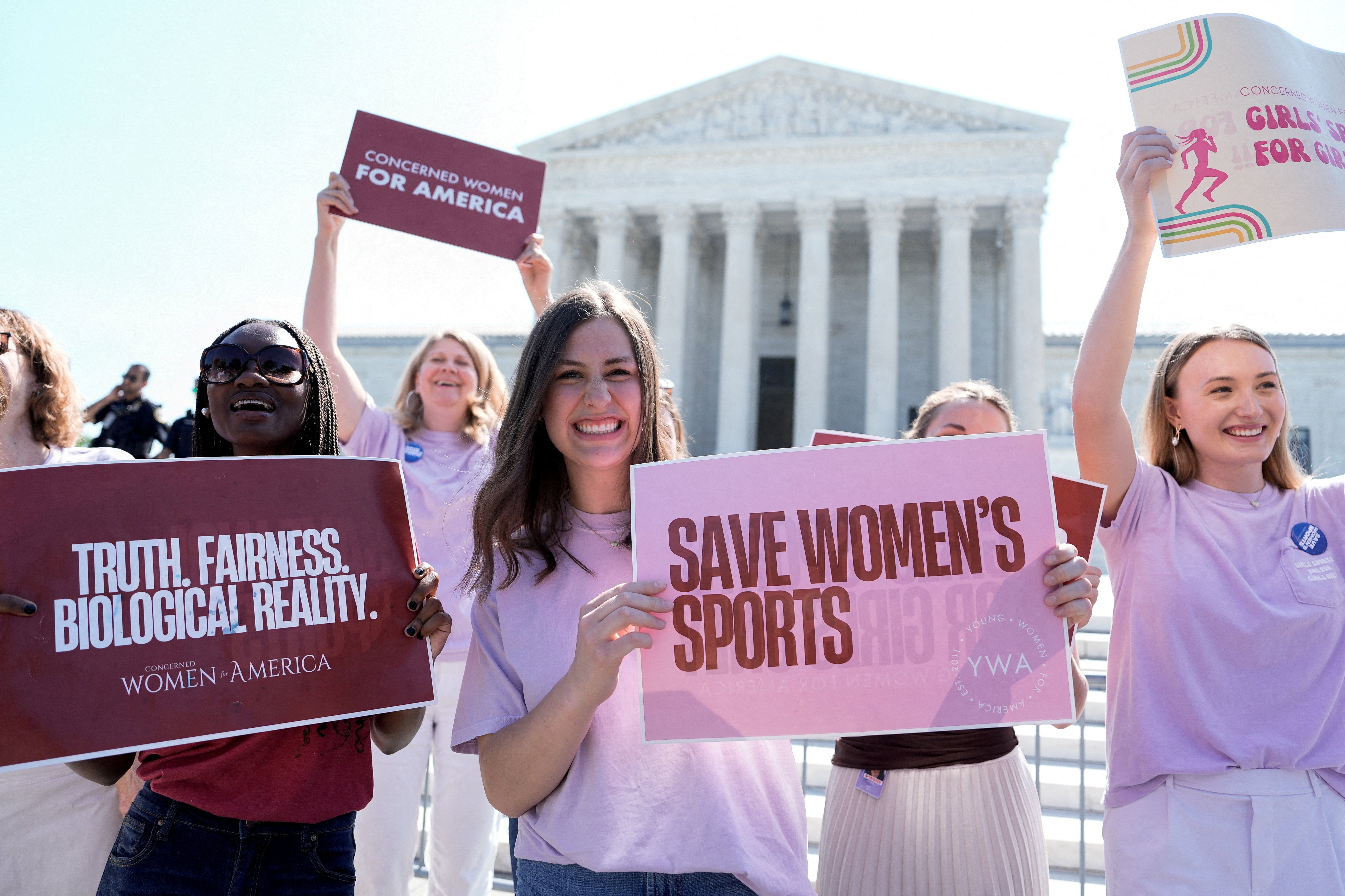 Women hold placards as they celebrate the U.S. Supreme Court's final rulings of its nine-month term, including a decision that cleared the way for states to impose restrictions on transgender student athletes