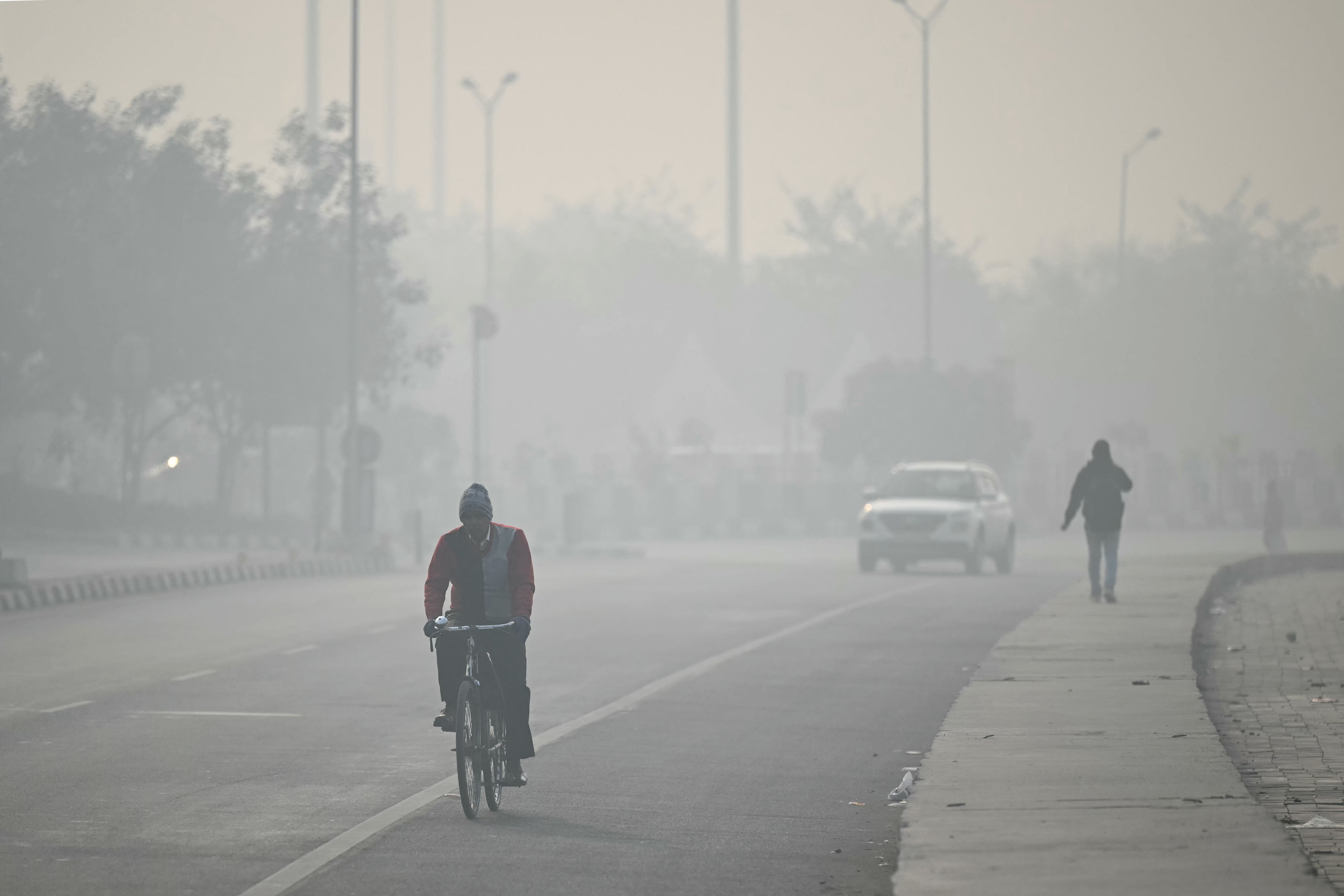 Commuters ride along a street amid dense smog in Delhi (AFP/Getty)