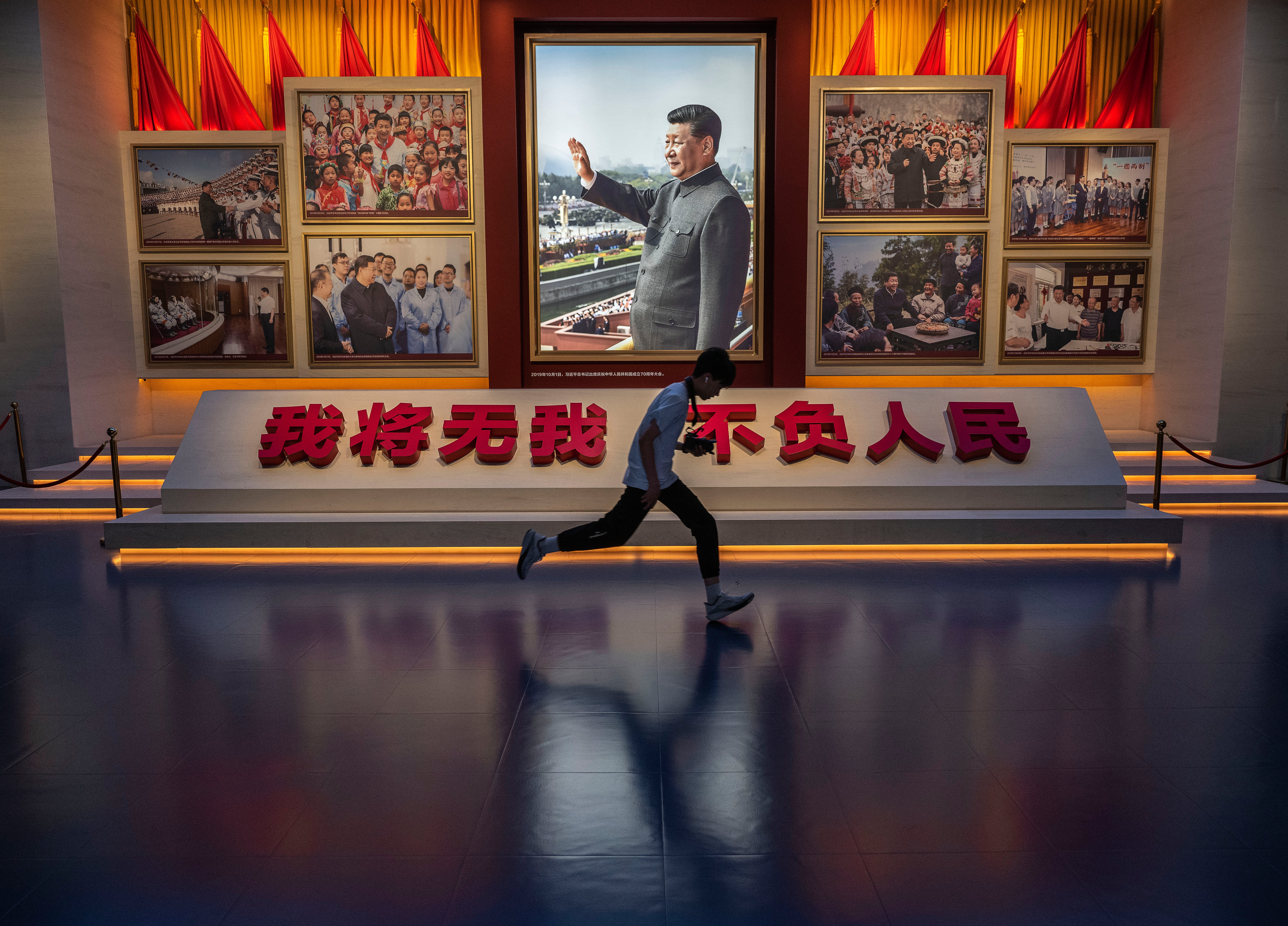 A boy runs past a portrait of Xi Jinping as he visits the Museum of the Communist Party on the 105th anniversary of its founding