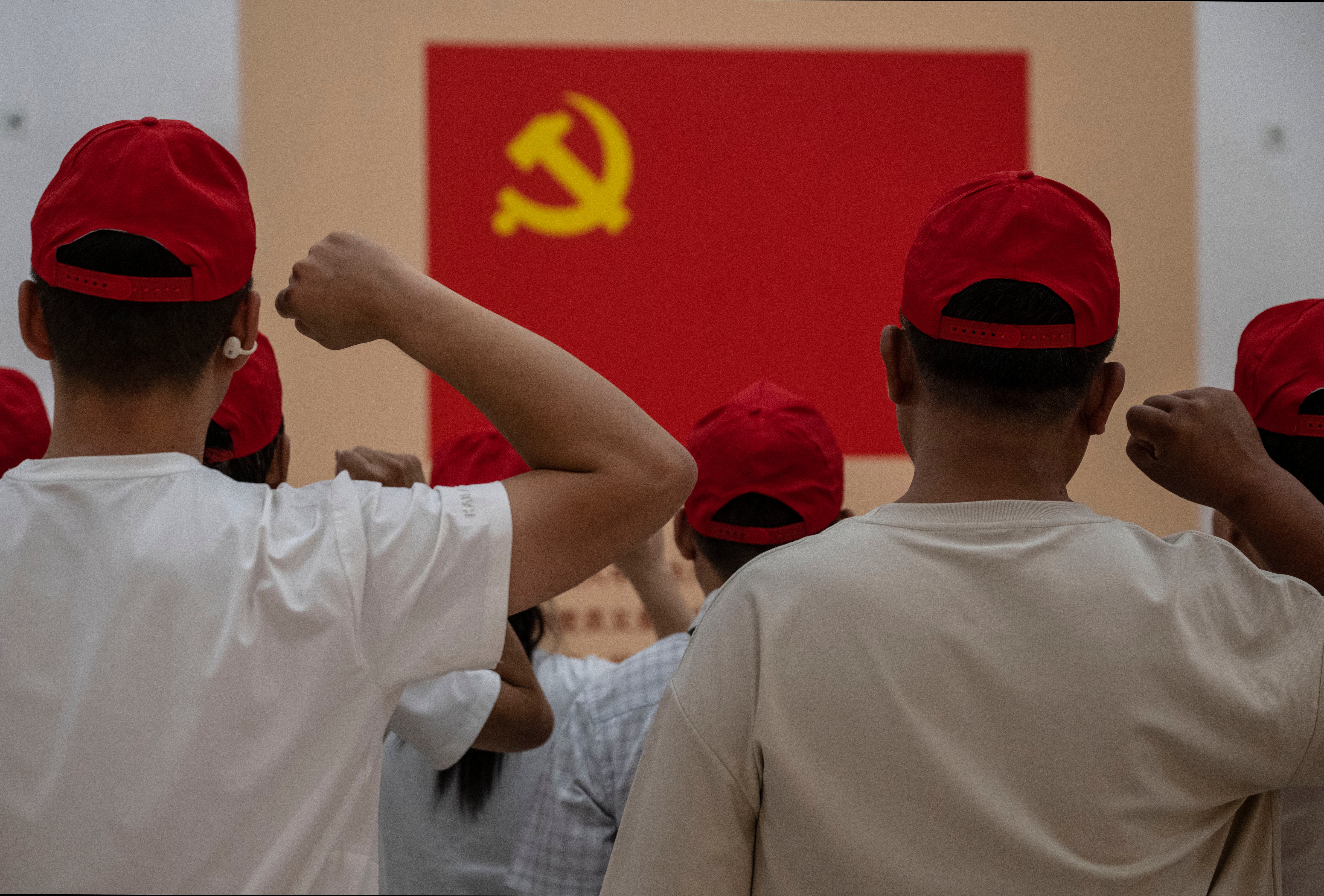 People say an oath of loyalty in front of a flag of the Communist Party of China