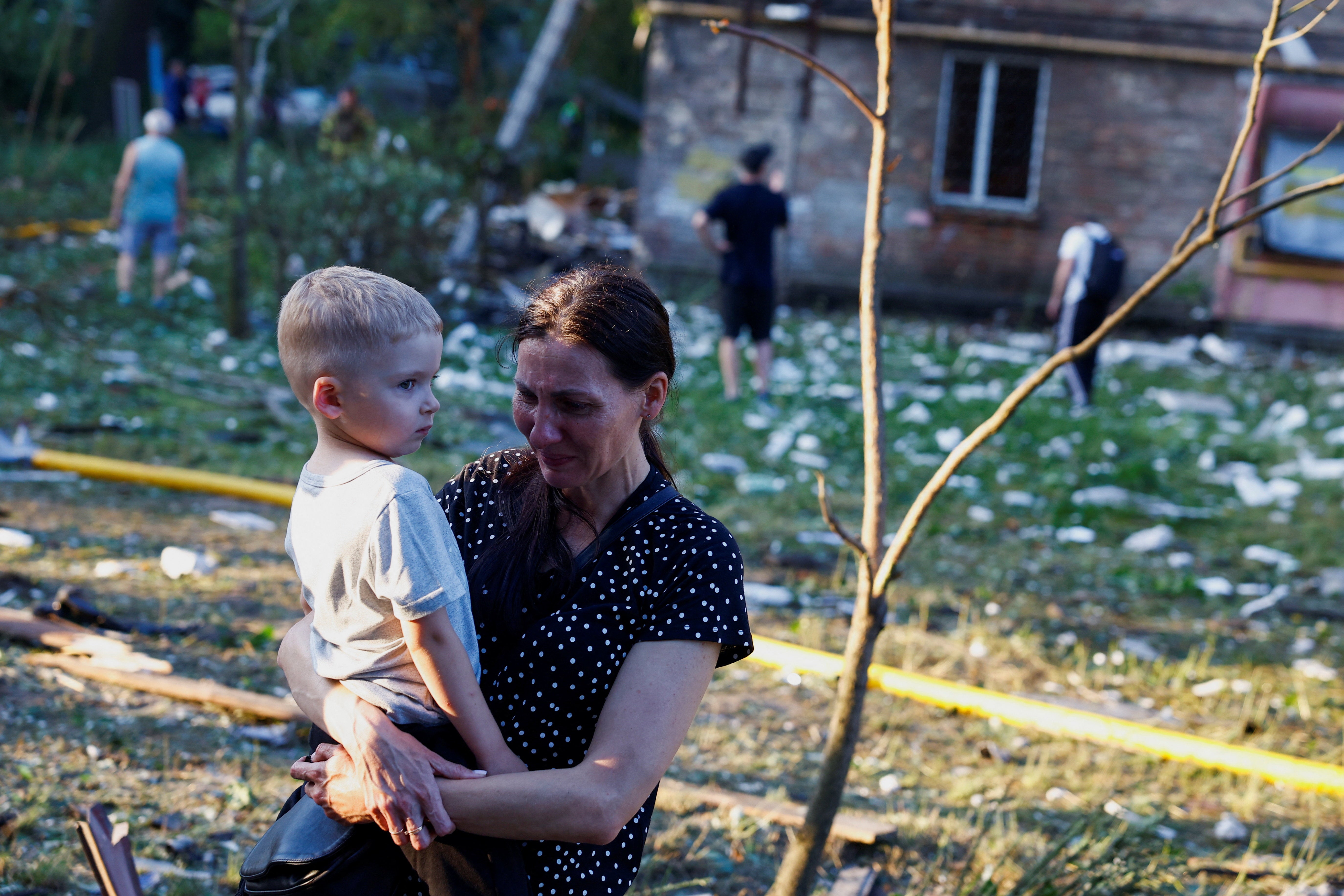 A woman cries holding a child near the site of an apartment building damaged during overnight Russian missile and drone strikes, amid Russia’s attack on Ukraine, in Kyiv, Ukraine, 2 July 2026
